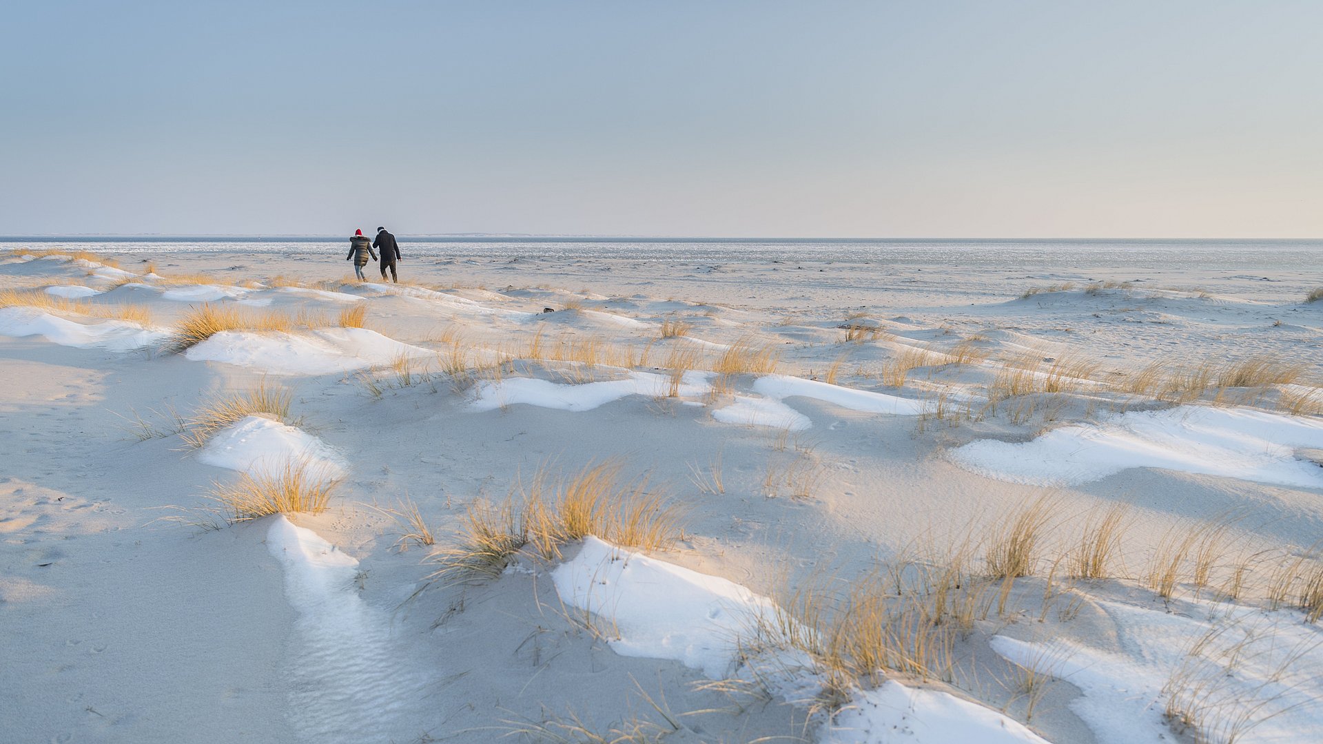 Ein Pärchen spaziert im Winter über die Dünen am Strand von Hörum auf Sylt