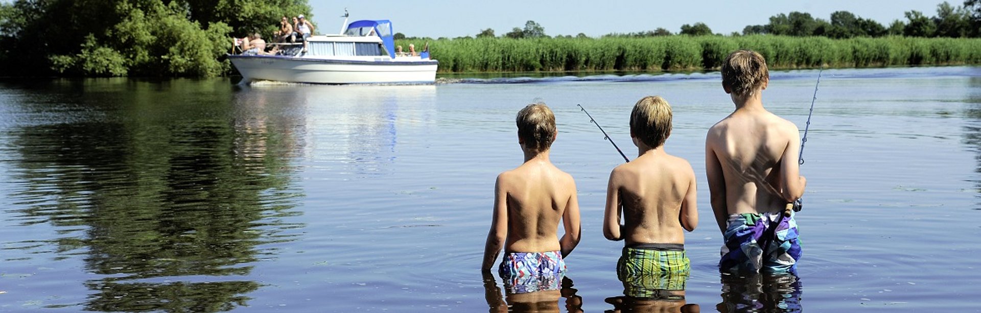 Drei Jungs gehen im Wasser angeln