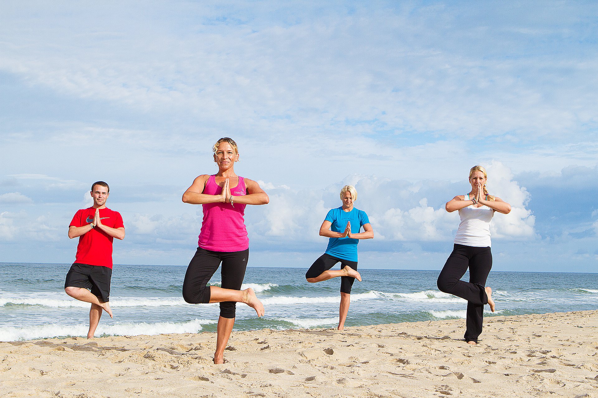 Drei Frauen und ein Mann machen Yoga am Strand von Westerland