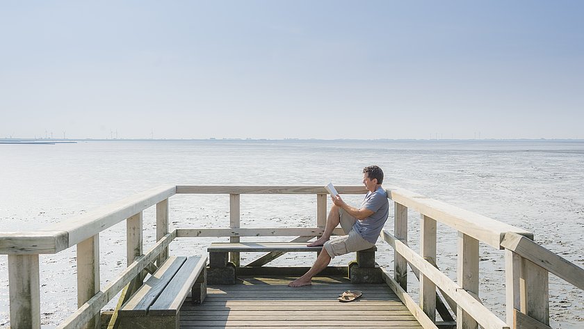 ein Mann liest ein Buch auf der Seebrücke Schobuell