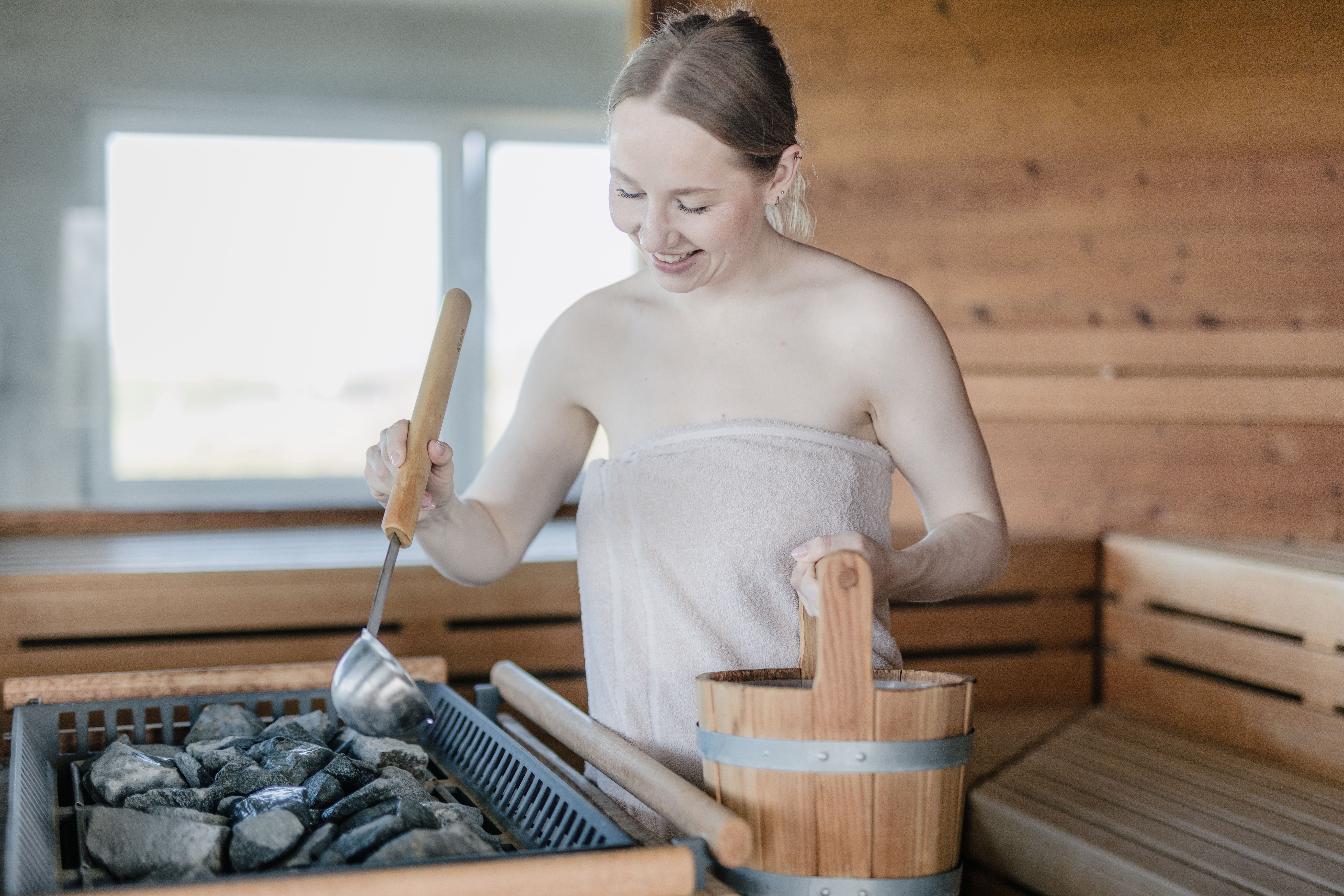Eine junge Frau macht einen Aufguss in der Sauna im Hotel Lundenbergsand