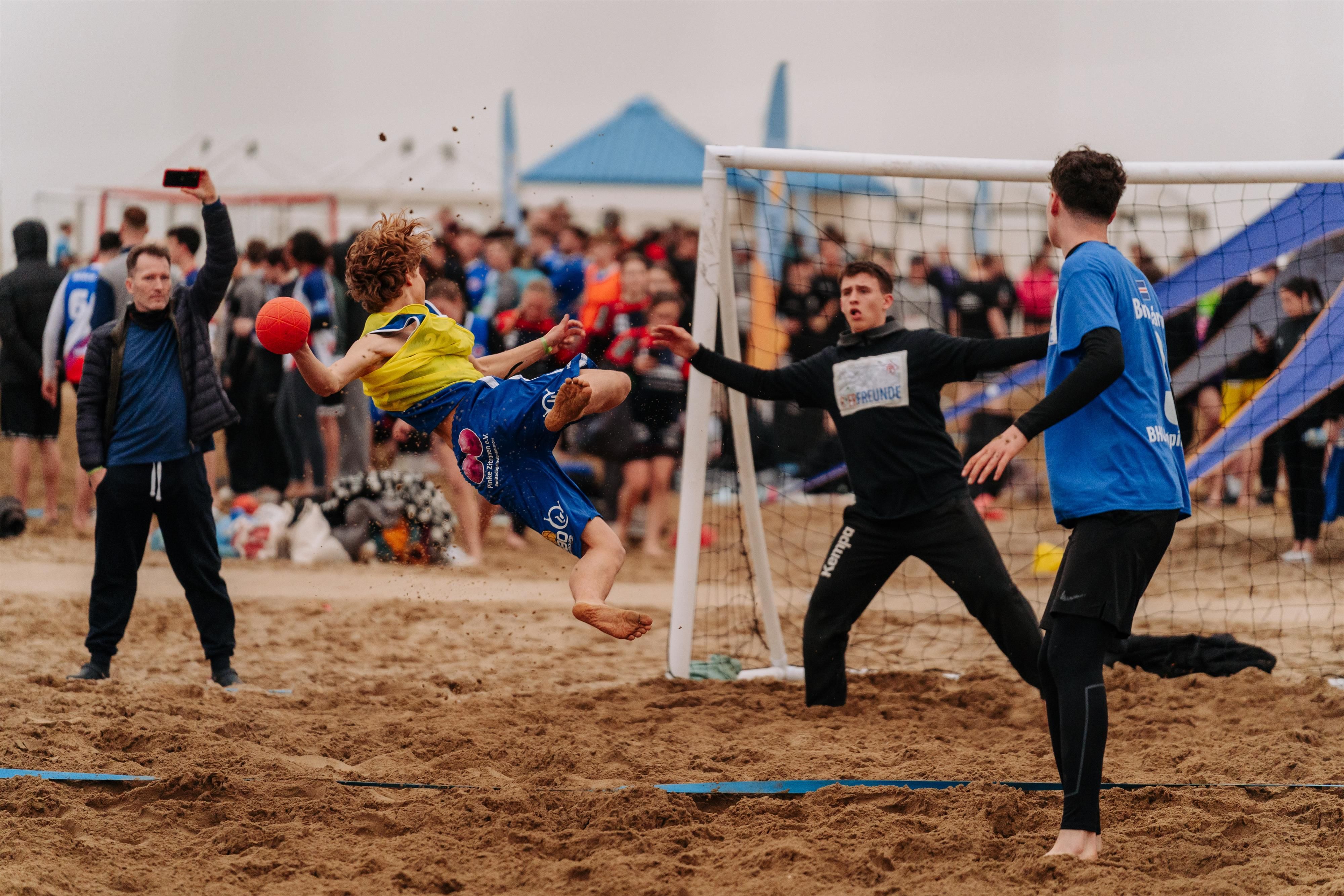 Jugendliche spielen Handball im Sand