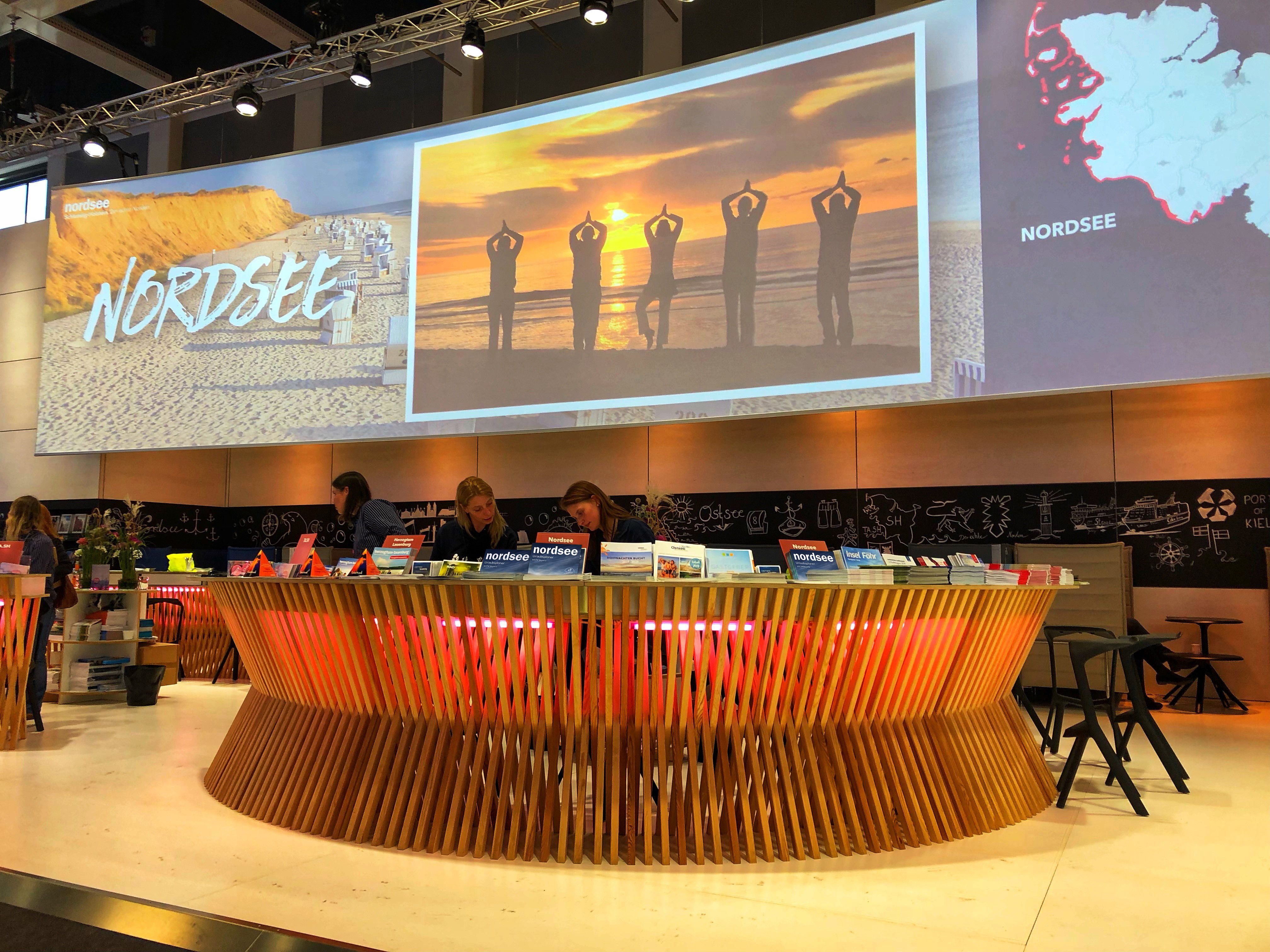 Nordsee Messestand mit vielen Prospekten und einer großen Leinwand im hintergrund