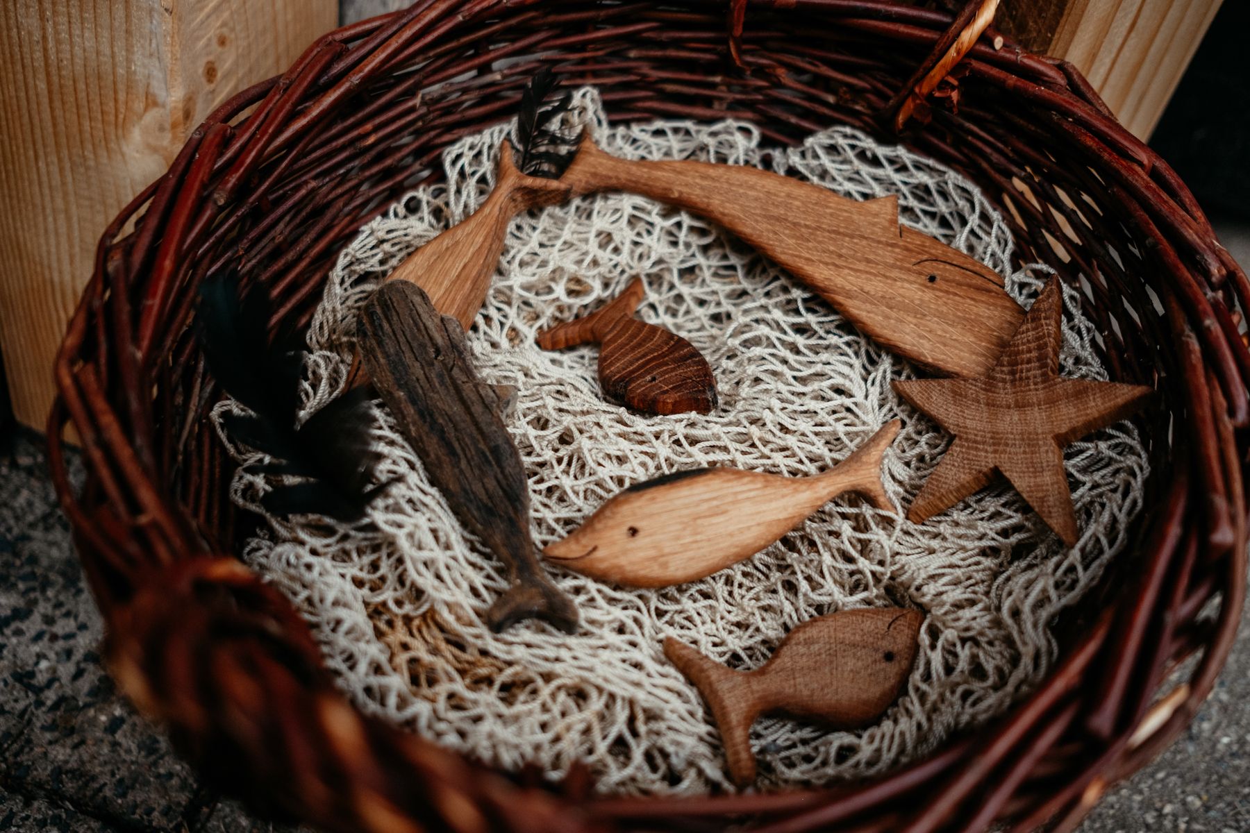Holzfische liegen auf einem Fischernetz in einem geflochtenen Korb.