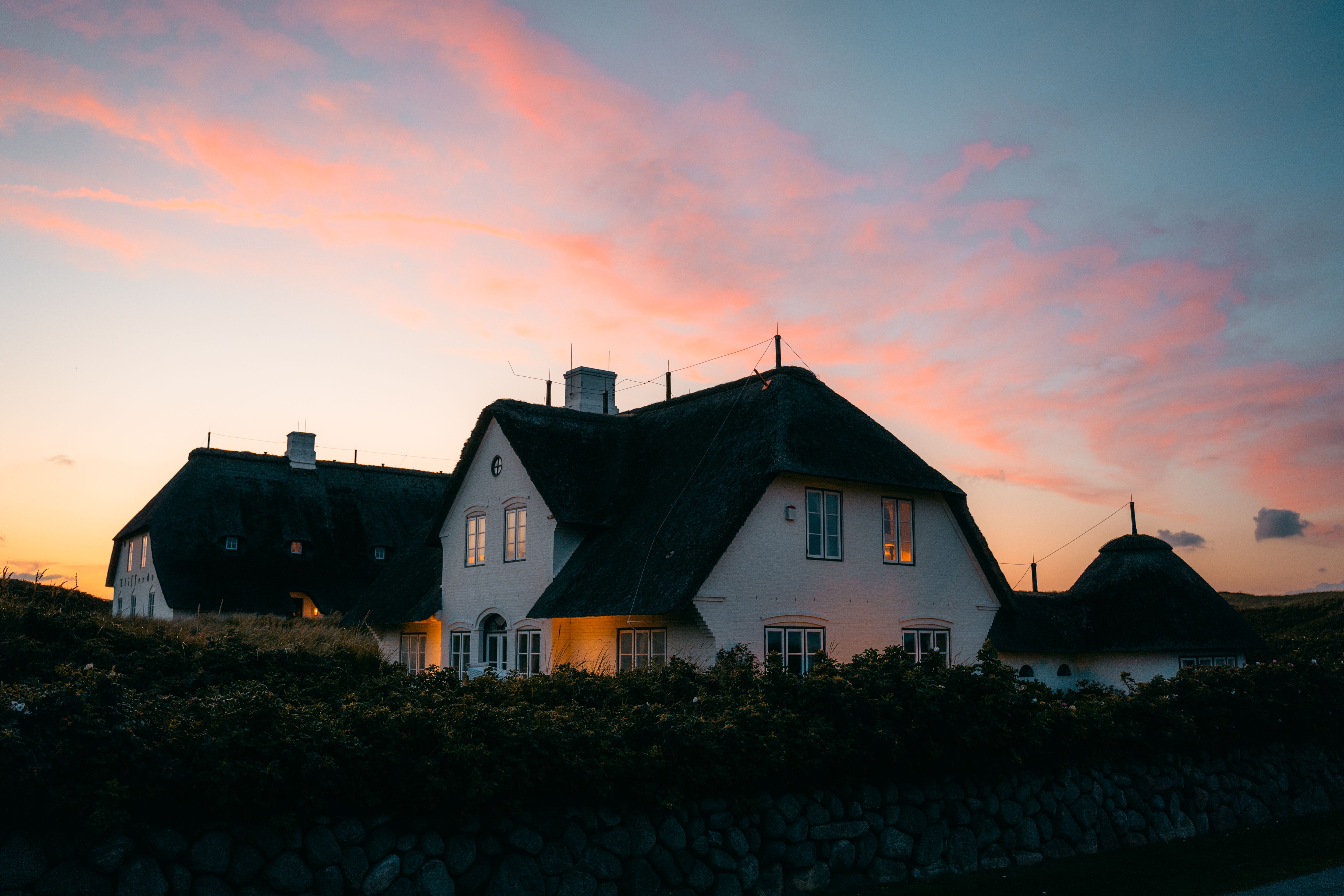 Sonnenuntergang hinter einem Reetdachhaus auf Sylt
