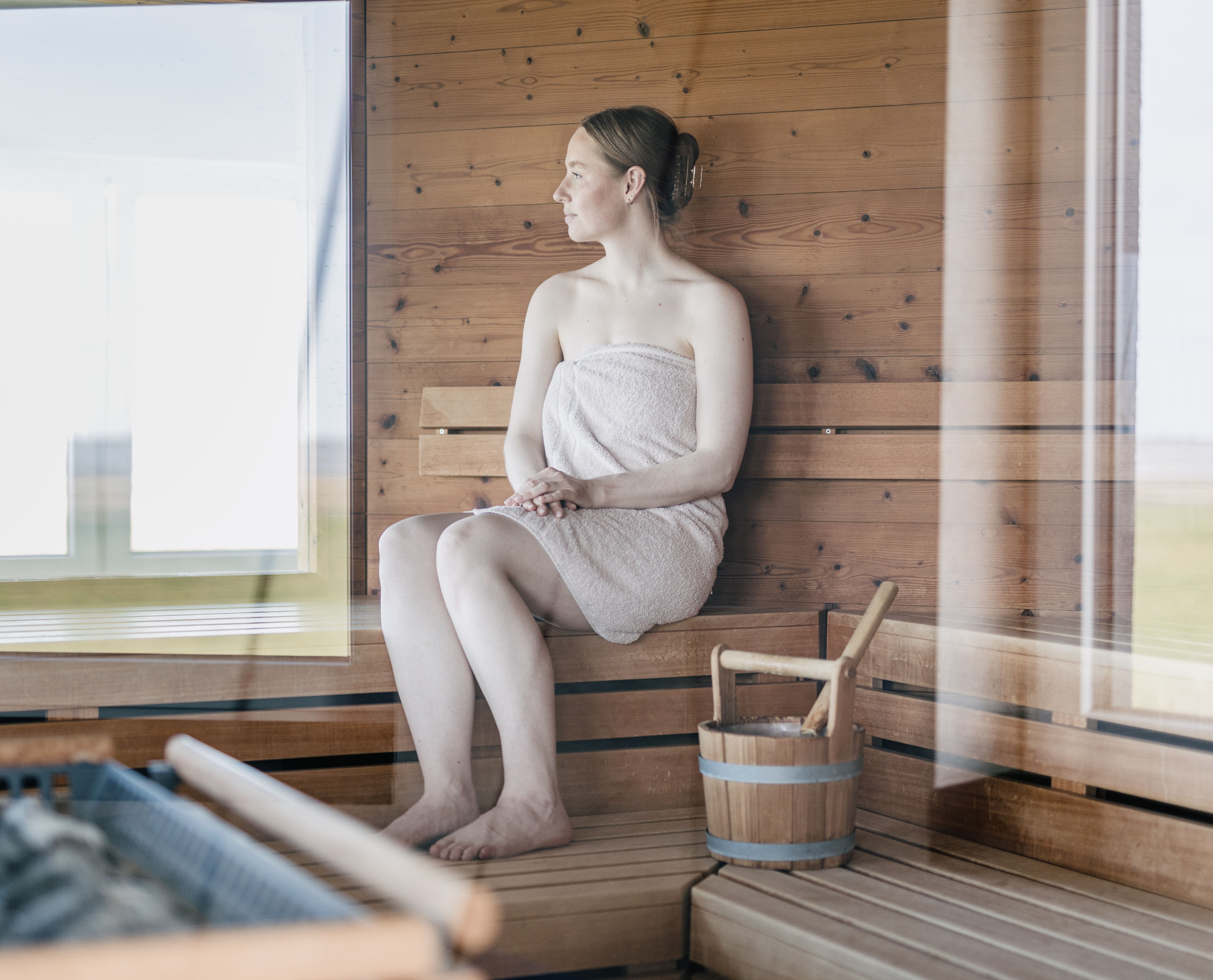 Eine Frau sitzt in der Sauna und schaut aus dem Fenster