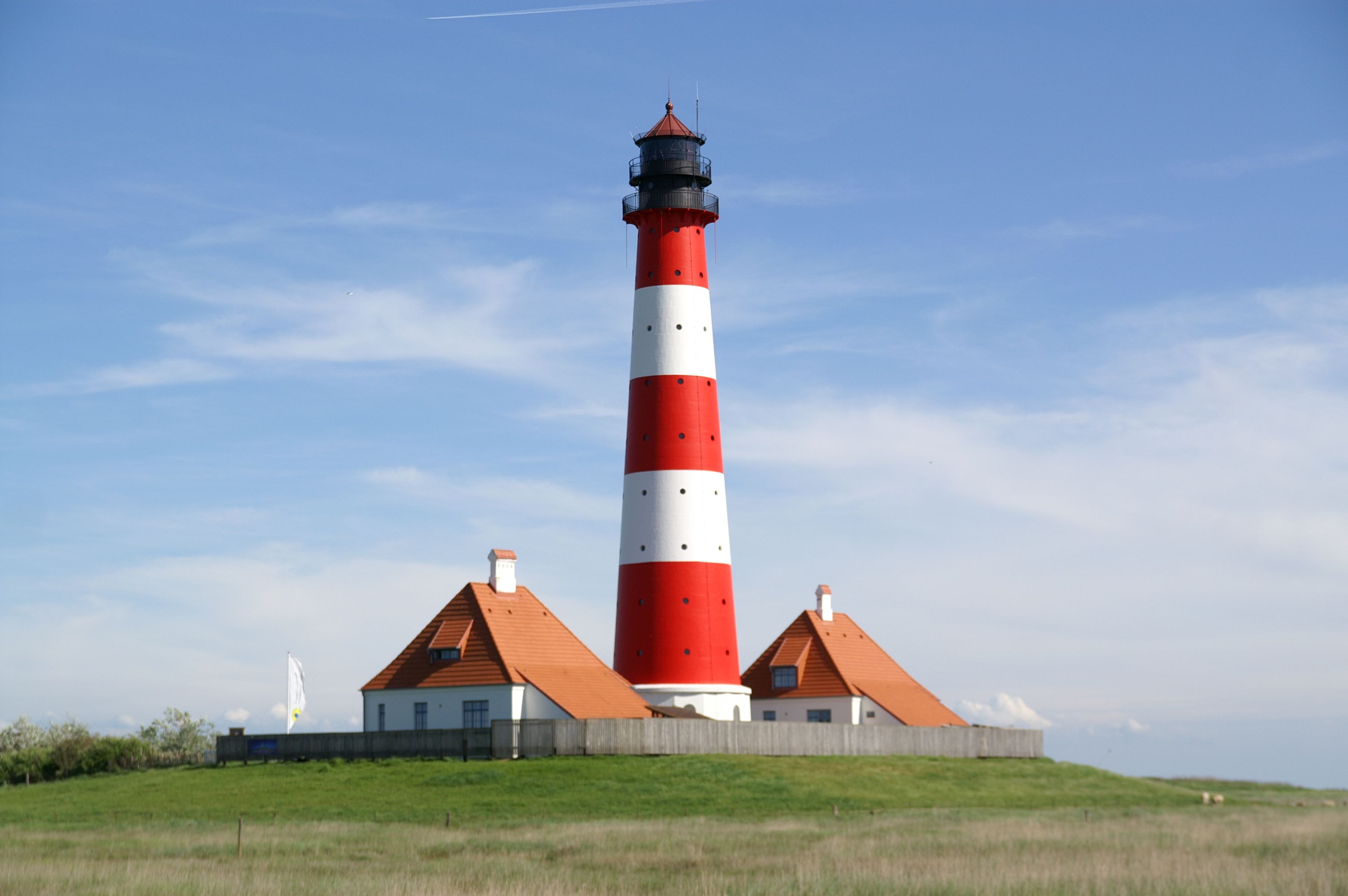 Der berühmte rot-weiße Leuchtturm Westerheversand auf Eiderstedt mit seinen beiden markanten Leuchtturmwärter Häusern.