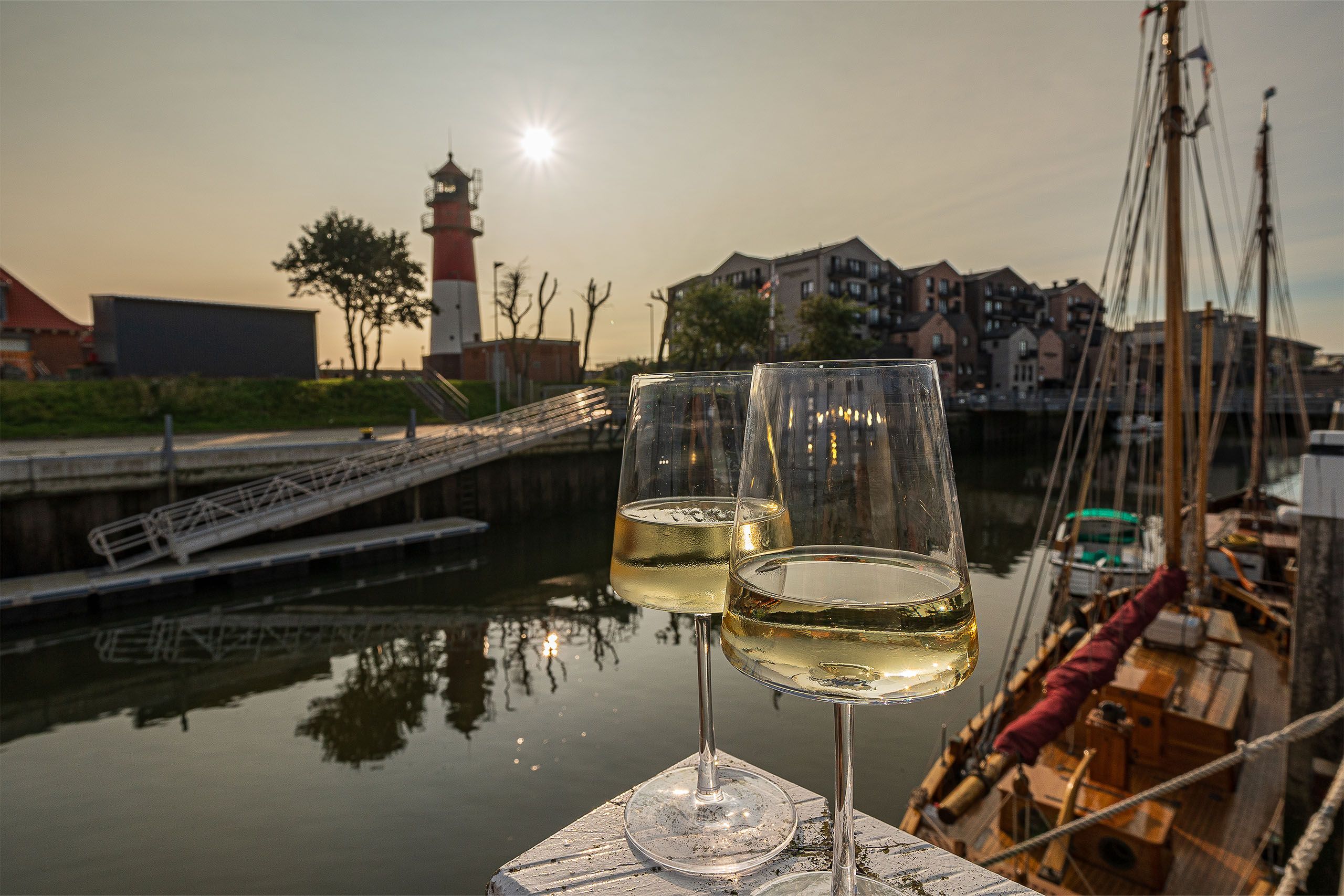 Zwei Weingläser stehen am alten Museumshafen von Büsum