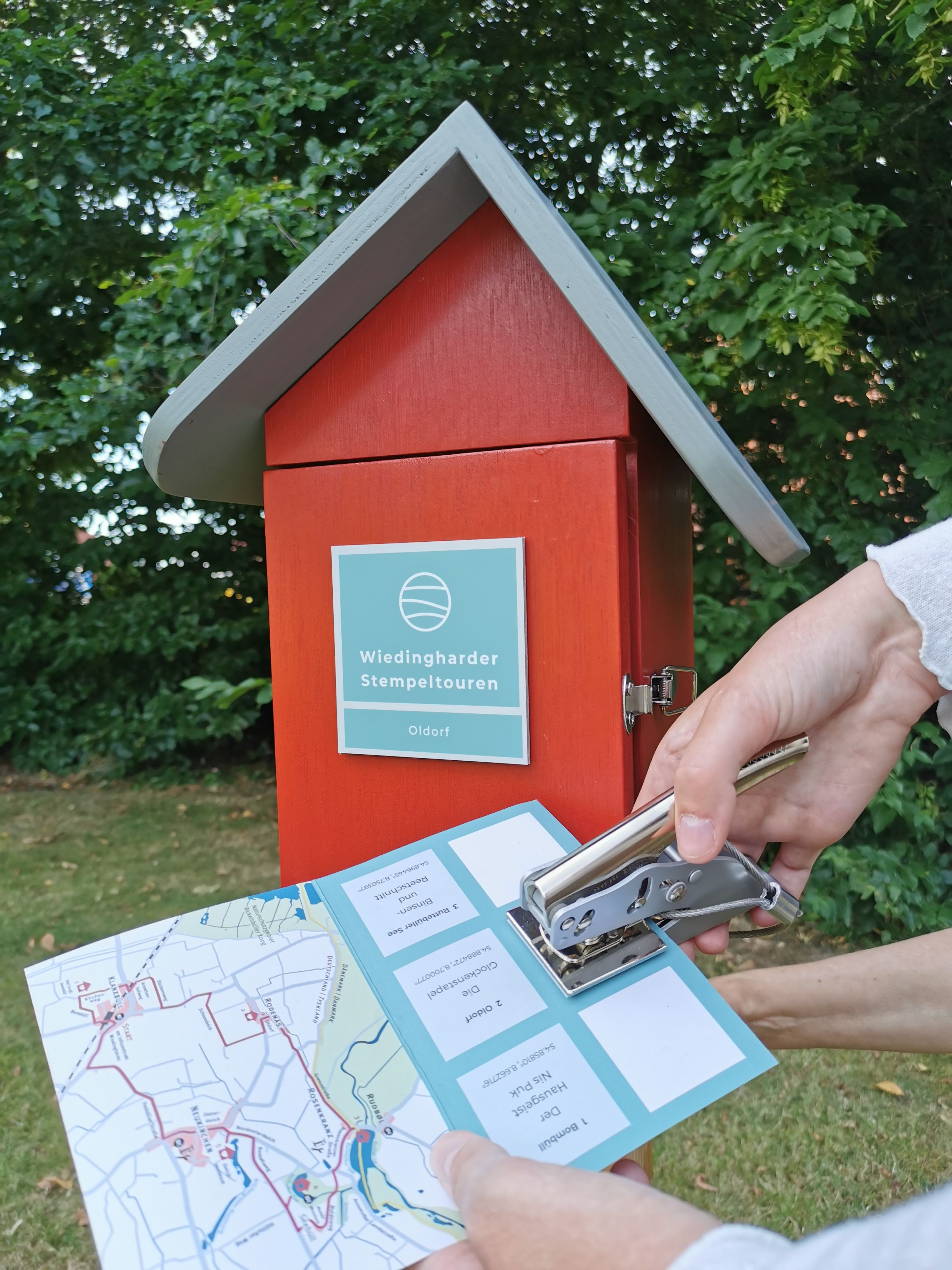 Ein Gast stempelt seine Stempelkarte der Wiedingharder Stempeltour. Foto: Infozentrum Wiedingharde 