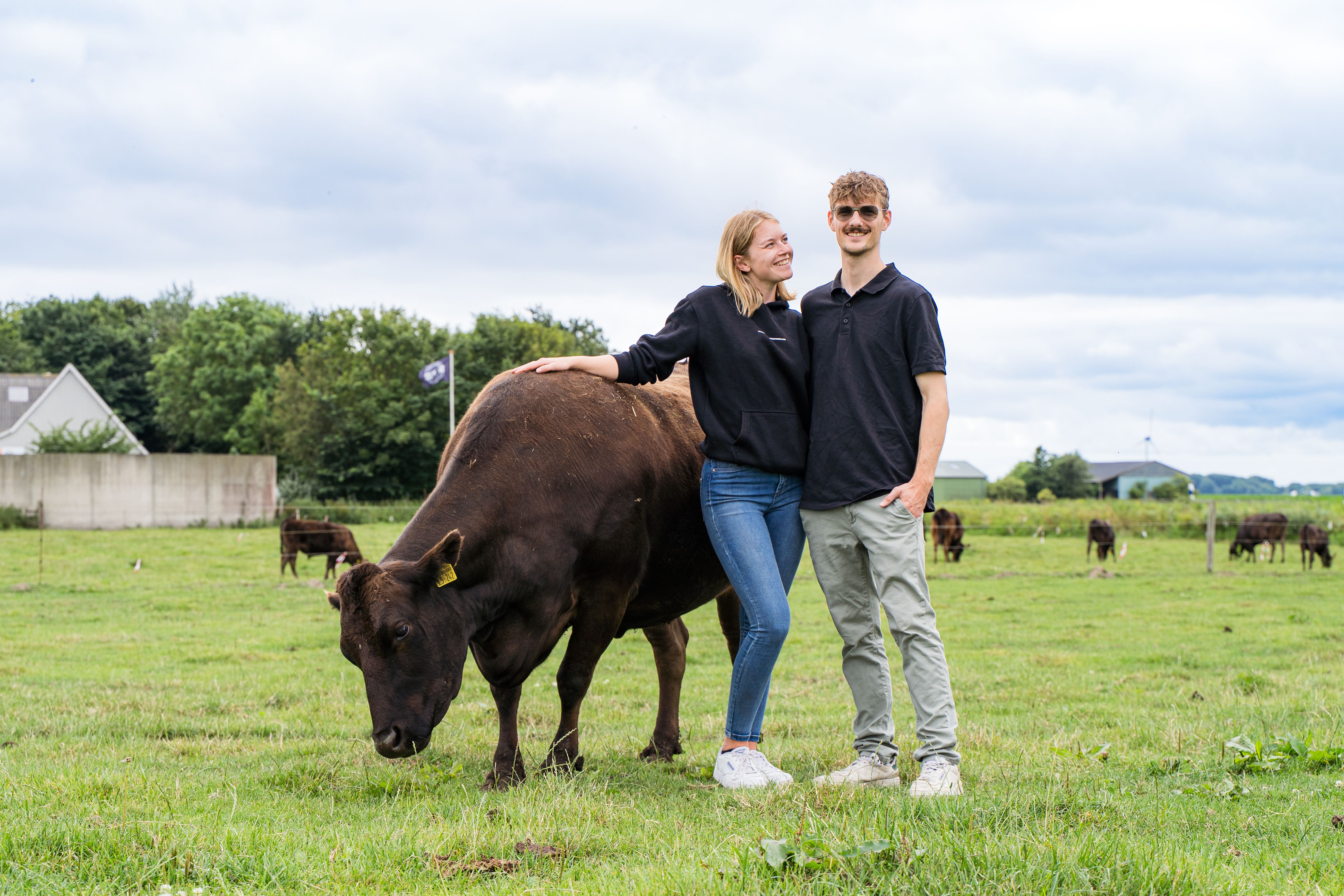 Die Inhaber des Hofladens stehen zusammen mit dem Wagyu Rind auf der Weide