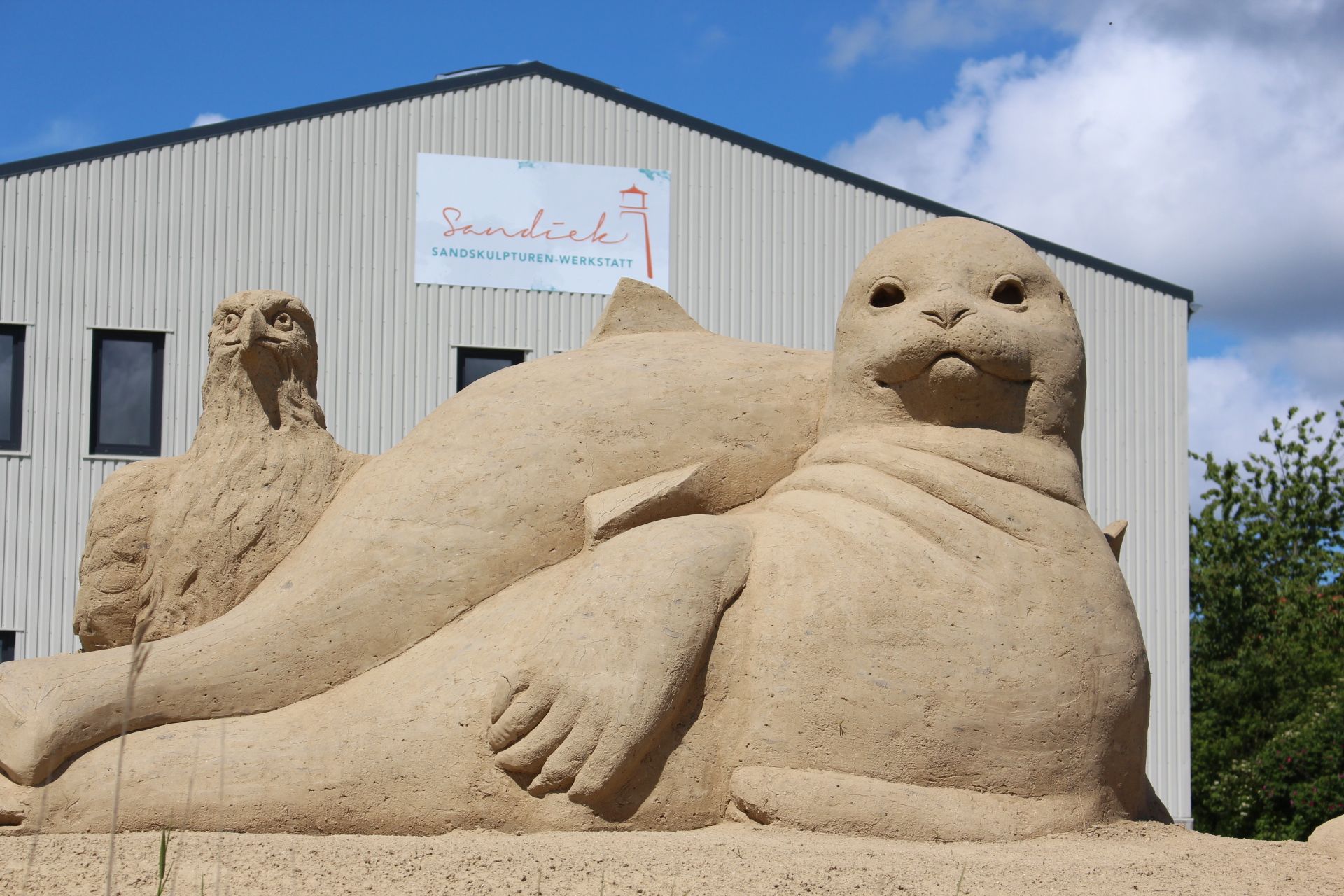Verschiedene Tiere als Sandskulpturen liegen vor der Halle, in der die Skulpturen kreiert werden