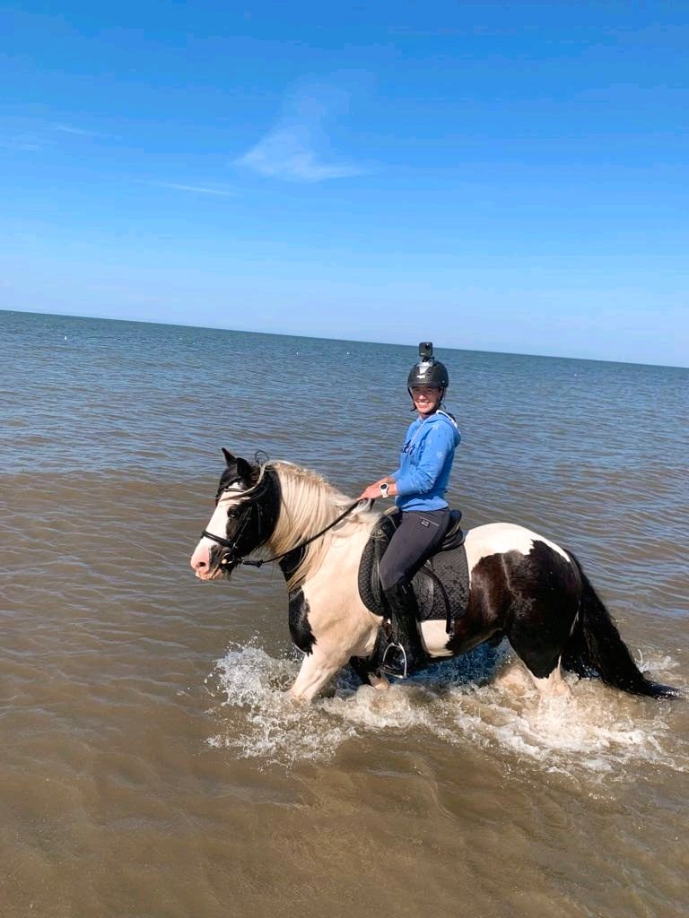 Eine Frau reitet durch das Wasser.