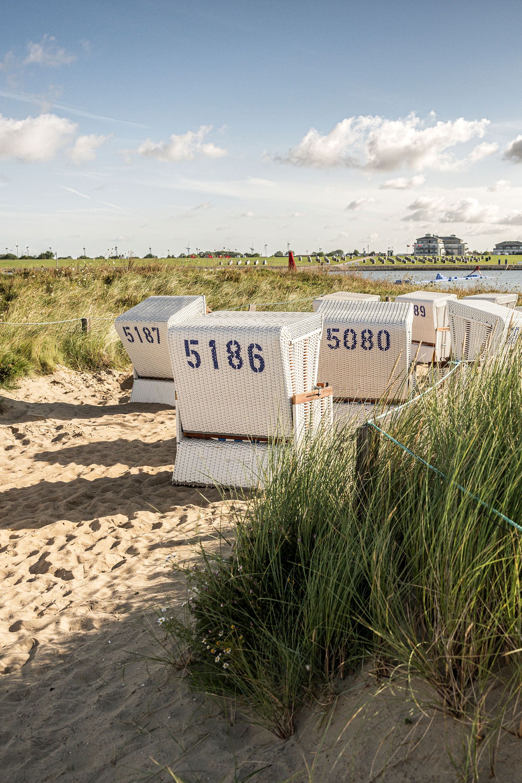 Mehrere Strandkörbe stehen auf der Büsumer Familienlagune im Strand zwischen Dünengras