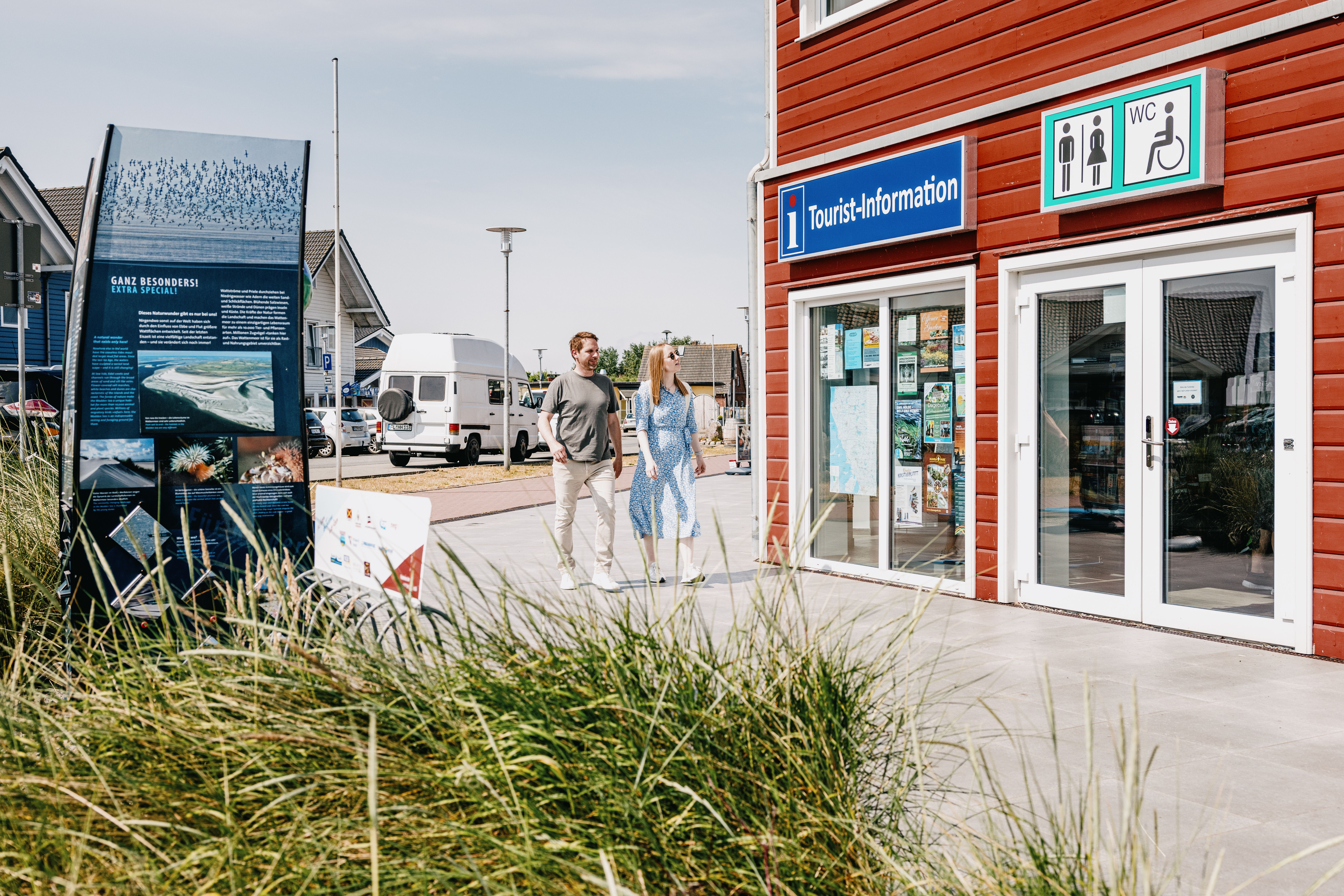 Zwei Personen spazieren vor dem Gebäude der Tourist-Information Dagebüll entlang