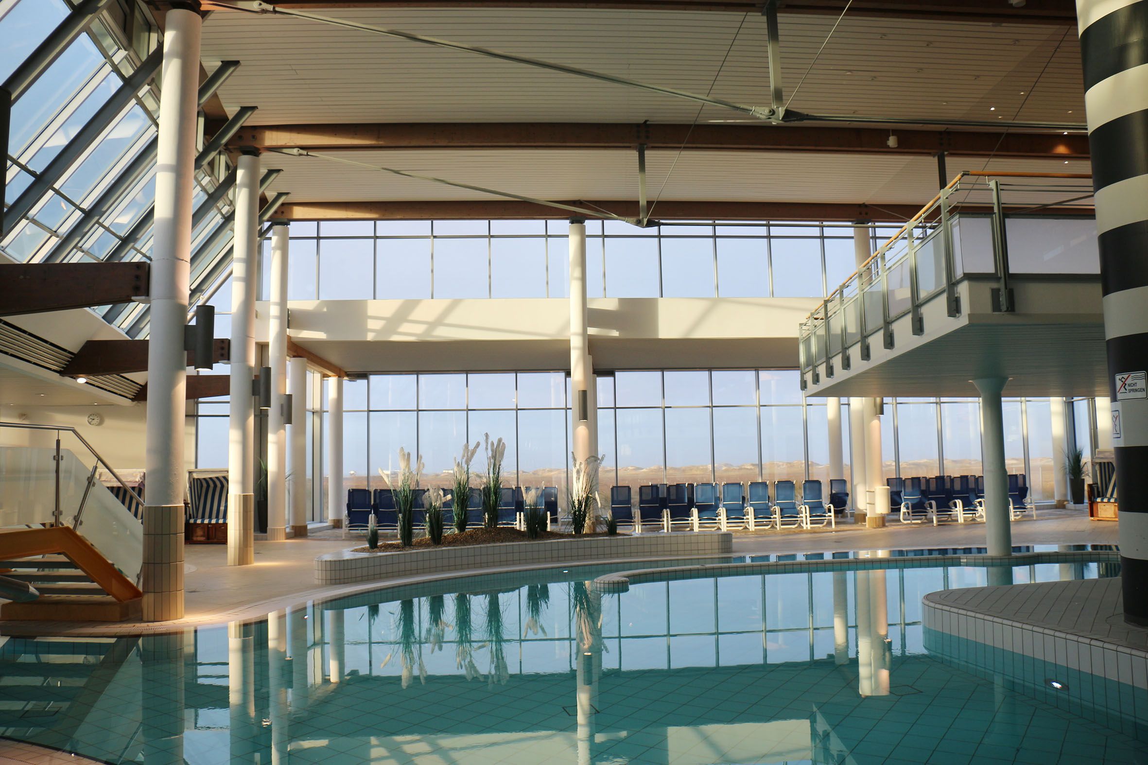 Blick auf den großen Innenbereich der Dünen-Therme mit großem Schwimmbecken und vielen Liegen