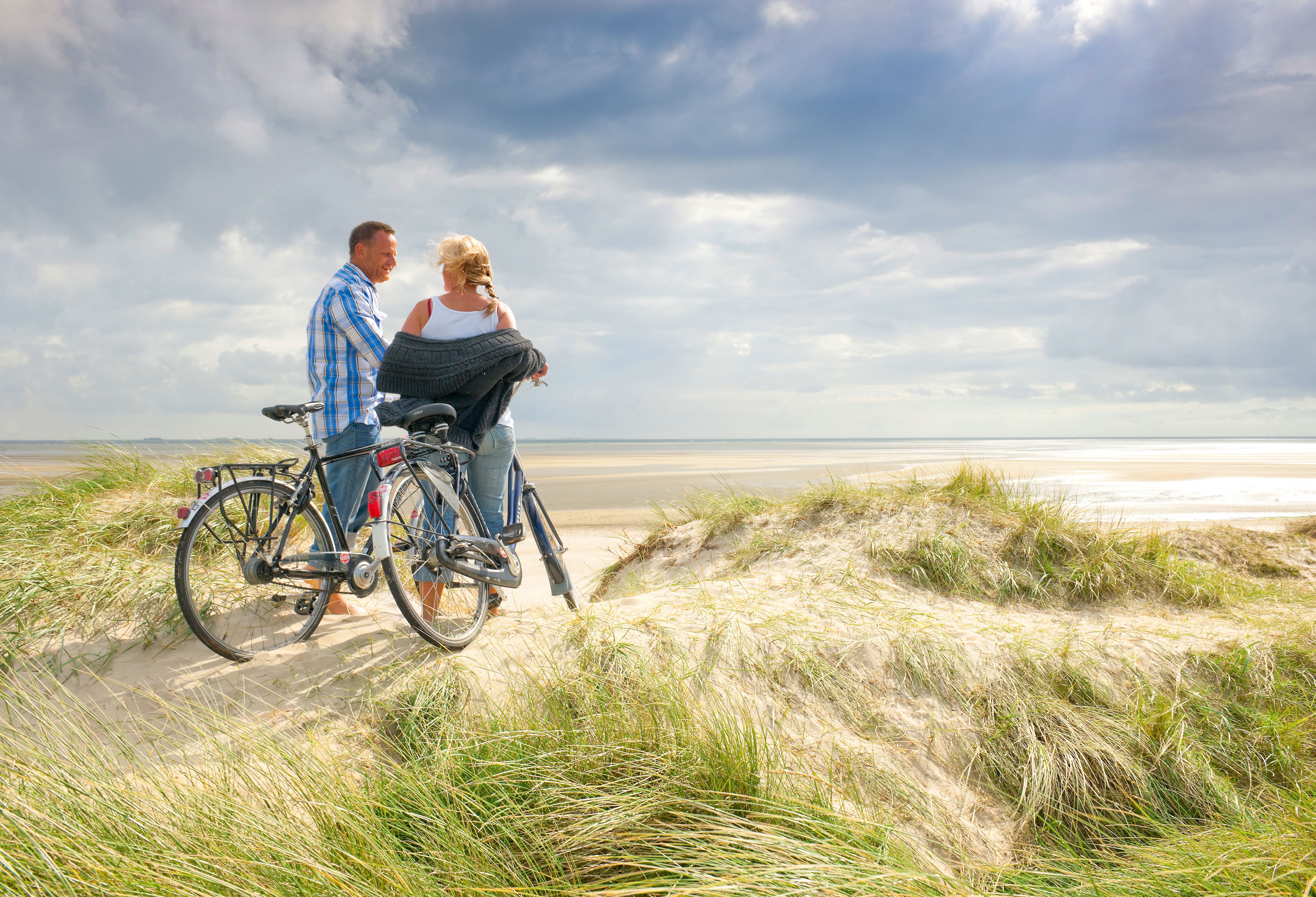 Ein Paar steht im sommer auf einer Düne am Gothing Kliff und schaut hinaus auf die Strandlandschaft. Foto: Föhr Tourismus GmbH | Oliver Franke