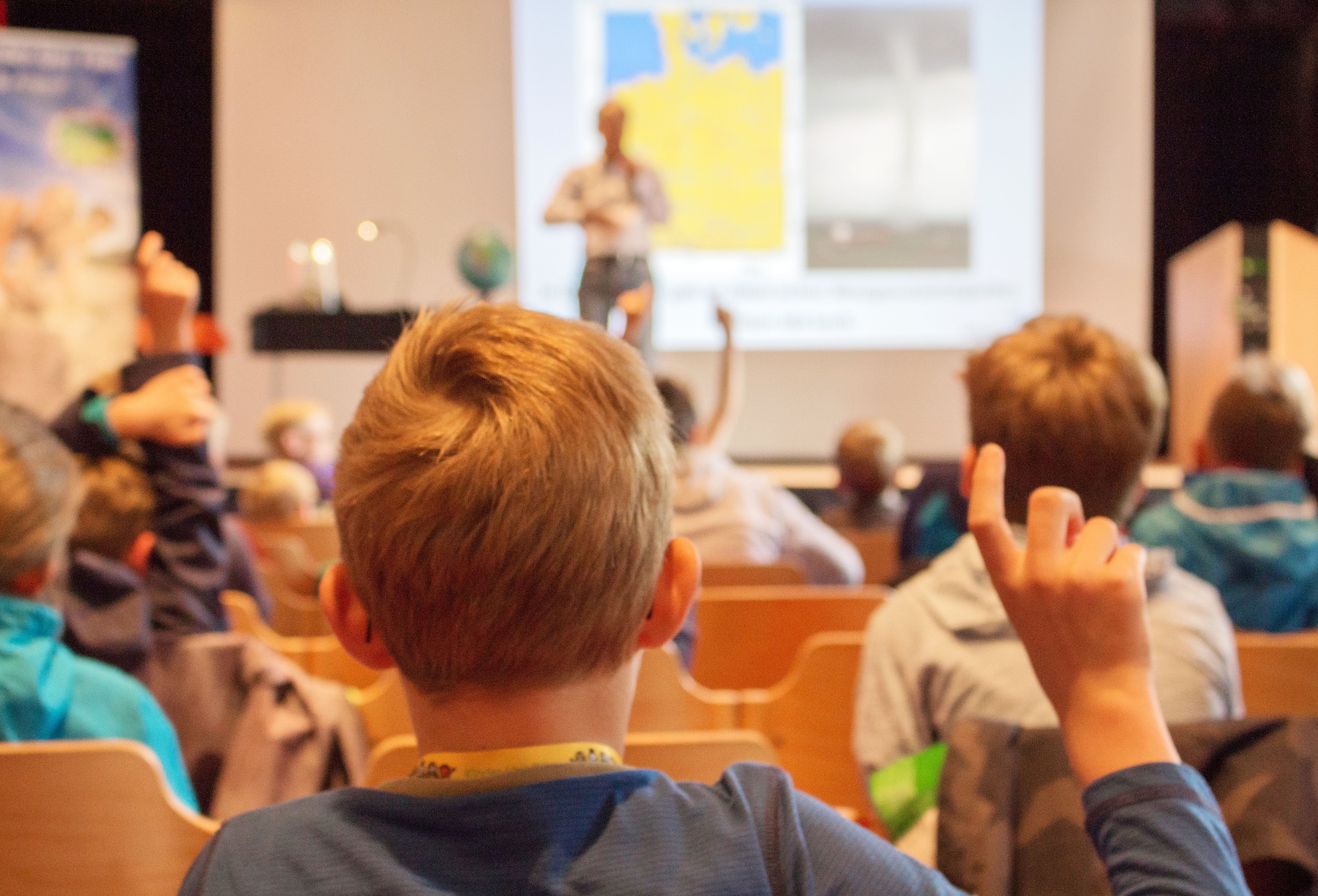 Man sieht Kinder, die in einer Vorlesung von Professor Latif die Hände/Finger heben. - Foto: Föhr Tourismus GmbH | Ann-Kathrin Meyerhof