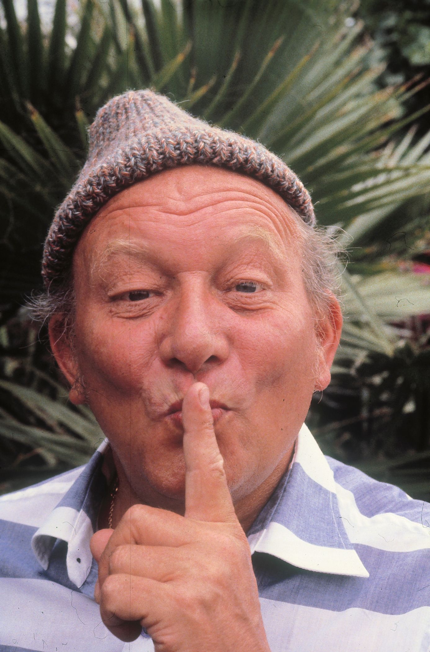 James Krüss mit Pudelmütze, hält sich einen Finger vor den Mund - "Pssst …!"t.