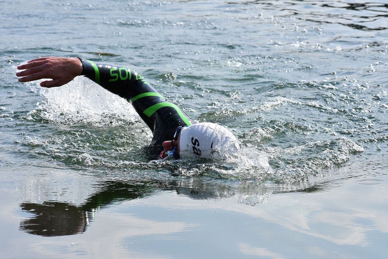 Schwimmer mit Haube und Neopren-Anzug schwimmt im Wasser