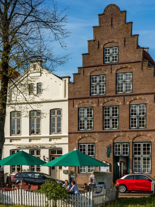 Das Hotel und Restaurant Hotel Holländische Stuben in Friedrichstadt, direkt von der Gracht aus fotografiert mit Restauranterrasse im Vordergrund. Foto: Hotel Holländische Stuben