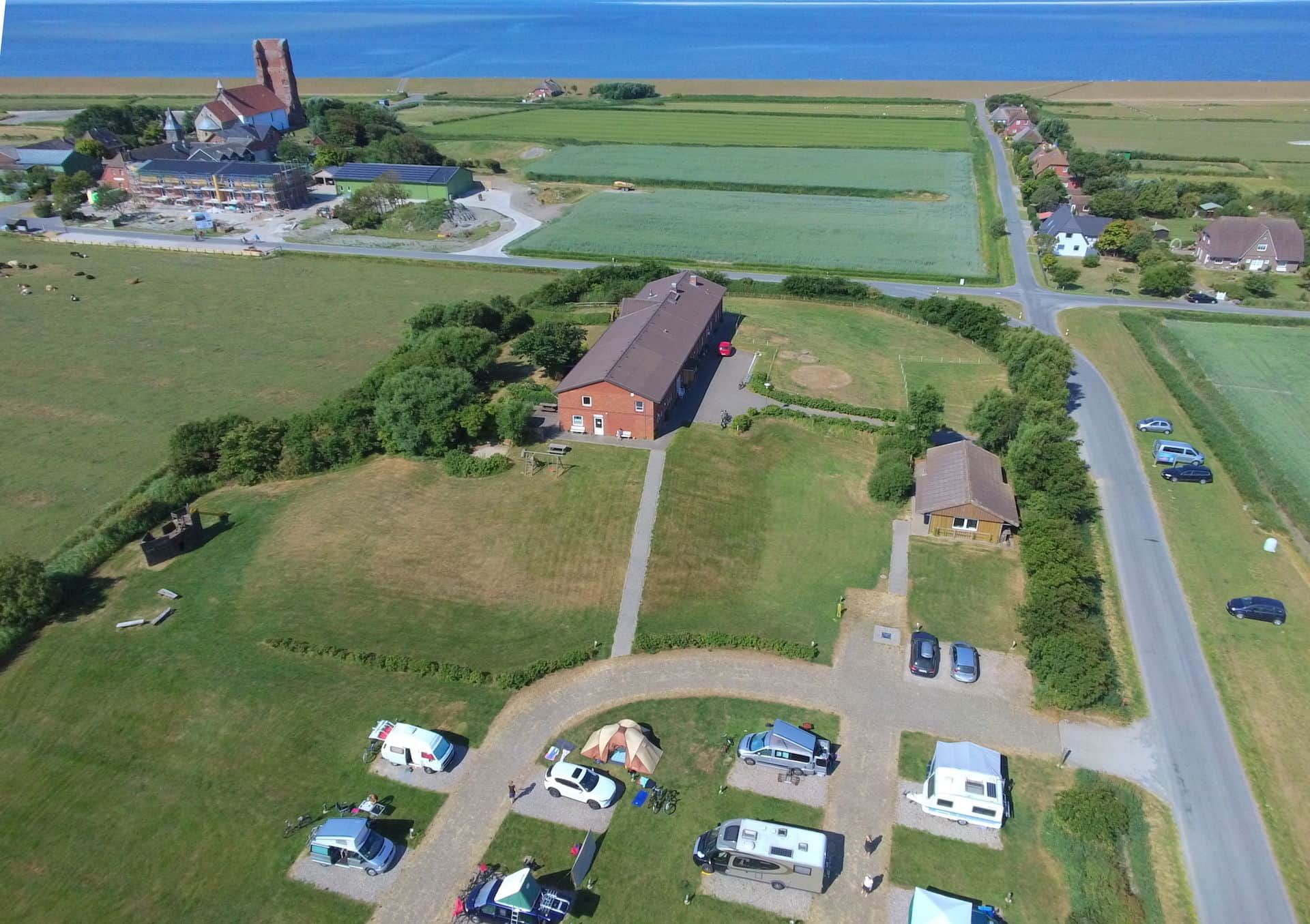 Luftbildaufnahme des Campingplatzes am Wattenmeerhaus auf Pellworm mitten im Grünen.
