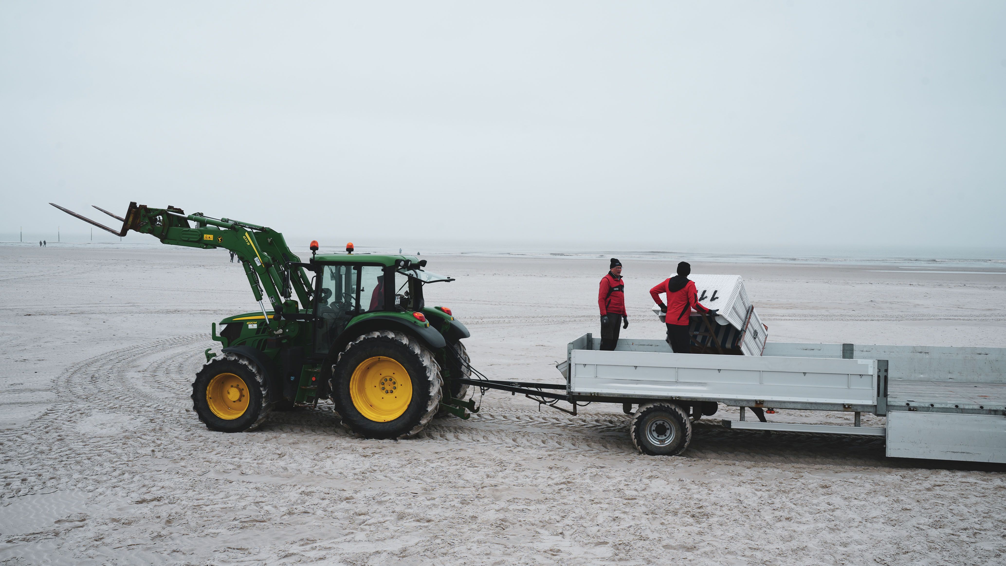 EIn Trecker fährt mehrere Strandkörbe an den Strand