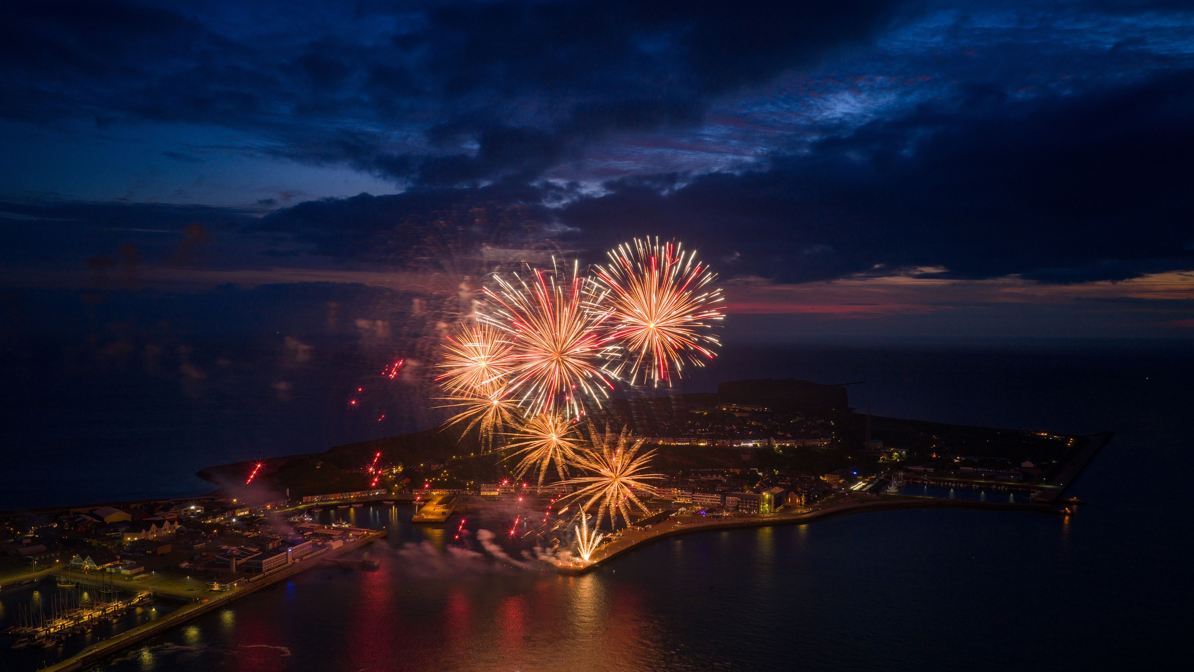 Eine Luftaufnahme in der Abendämmerung, zwigt ein Feuerwerk über Helgoland.