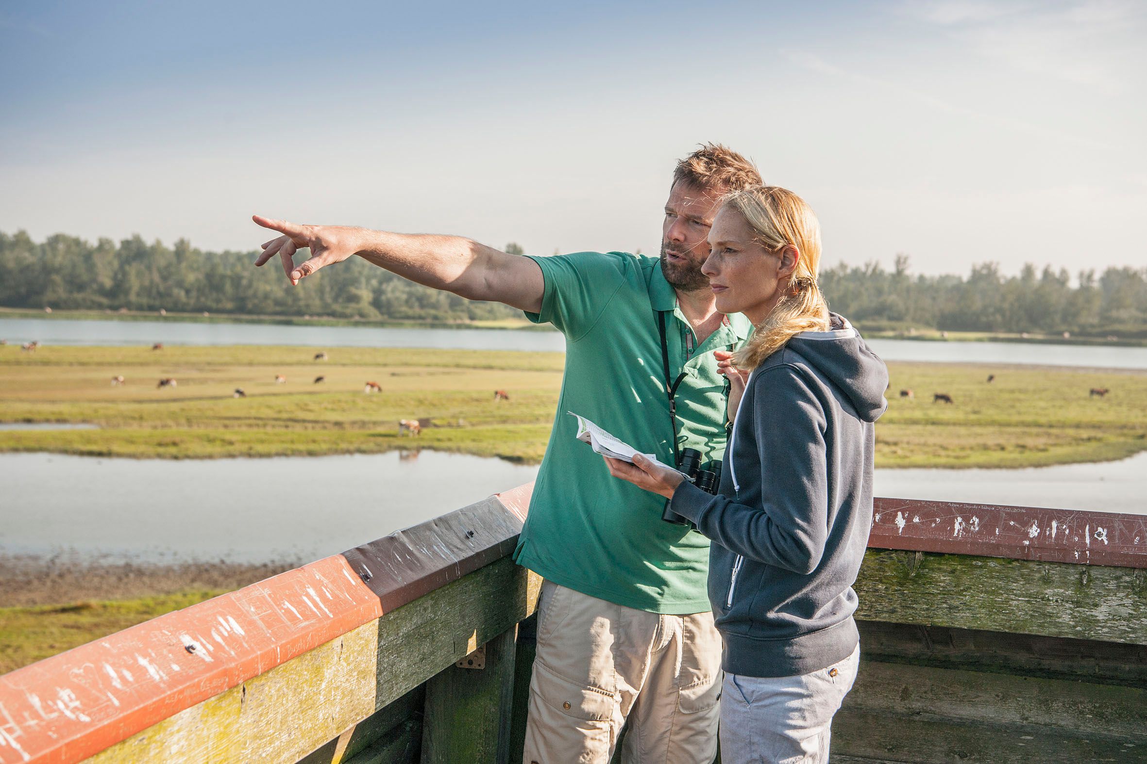 Ein Mann zeigt seiner Frau auf dem Aussichtsturm im Katinger Watt die Landschaft.
