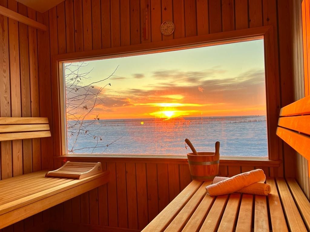 Saune in Dagebüll, aus dem großen Panoramafenster sieht man das Meer über dem die Sonne untergeht.