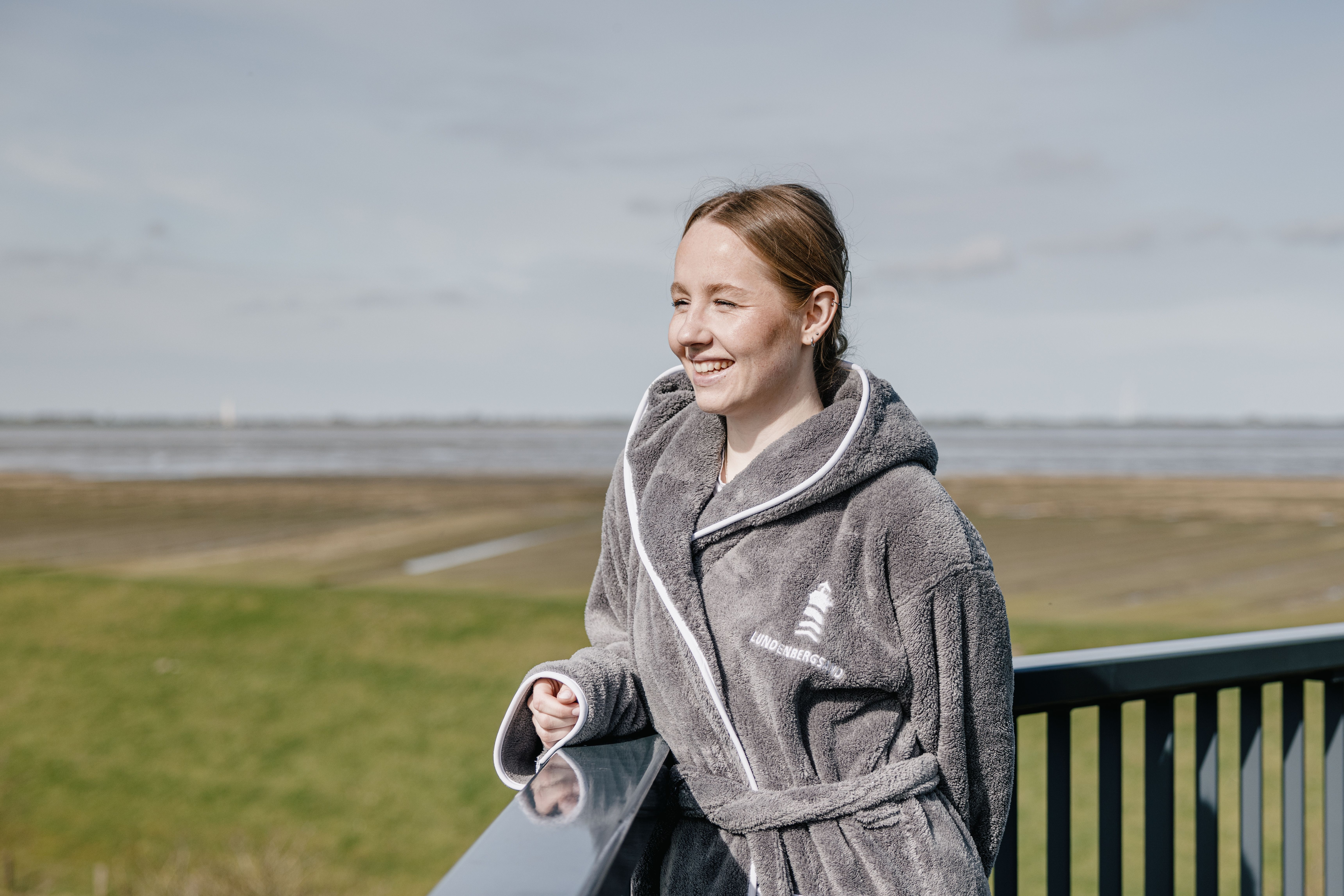 Eine Frau genießt im Bademantel die Aussicht vom Hotel Lundenbergsand