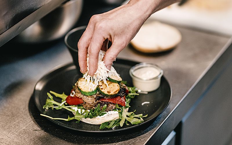 Ein Sterne Burger bekommt sein letztes Finish bevor die obere Hälfte des "Brötchens" aufgelegt wird