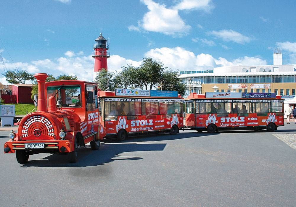 Die rote Büsumer Kleinbahn steht am alten Museumshafen vor dem Leuchtturm