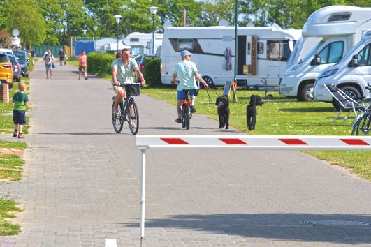 Gäste laufen zwischen den Wohnmobilen auf dem Campingplatz umher