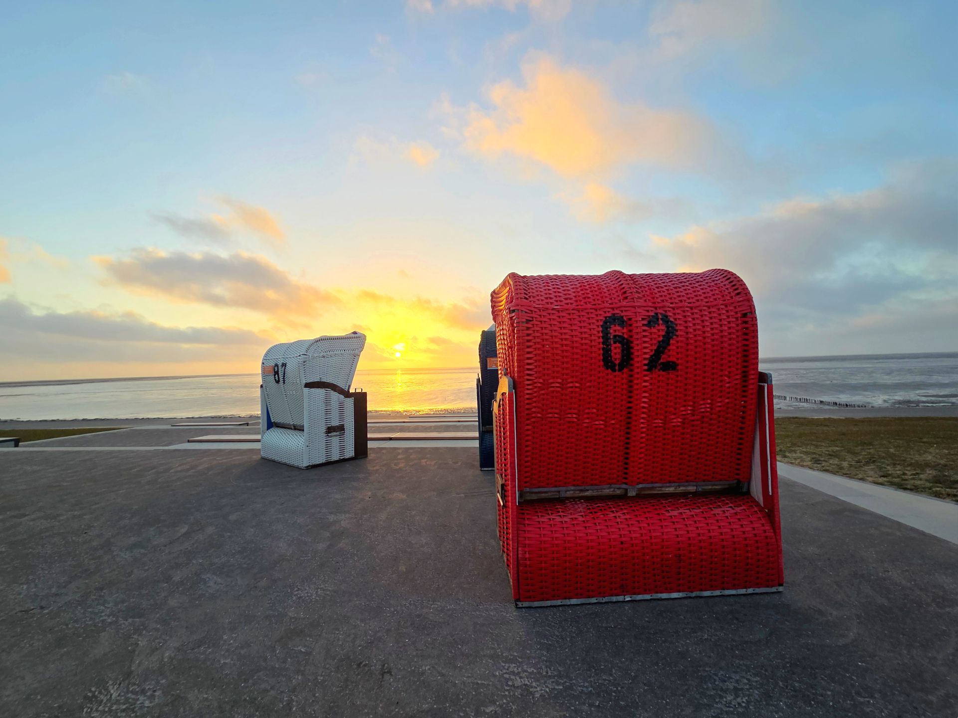 Ein roter und ein weißer Strandkorb stehen bei Sonnenuntergang auf der neuen Promenande in Frierichskoog- Foto: Martina Sahm – GLC AG