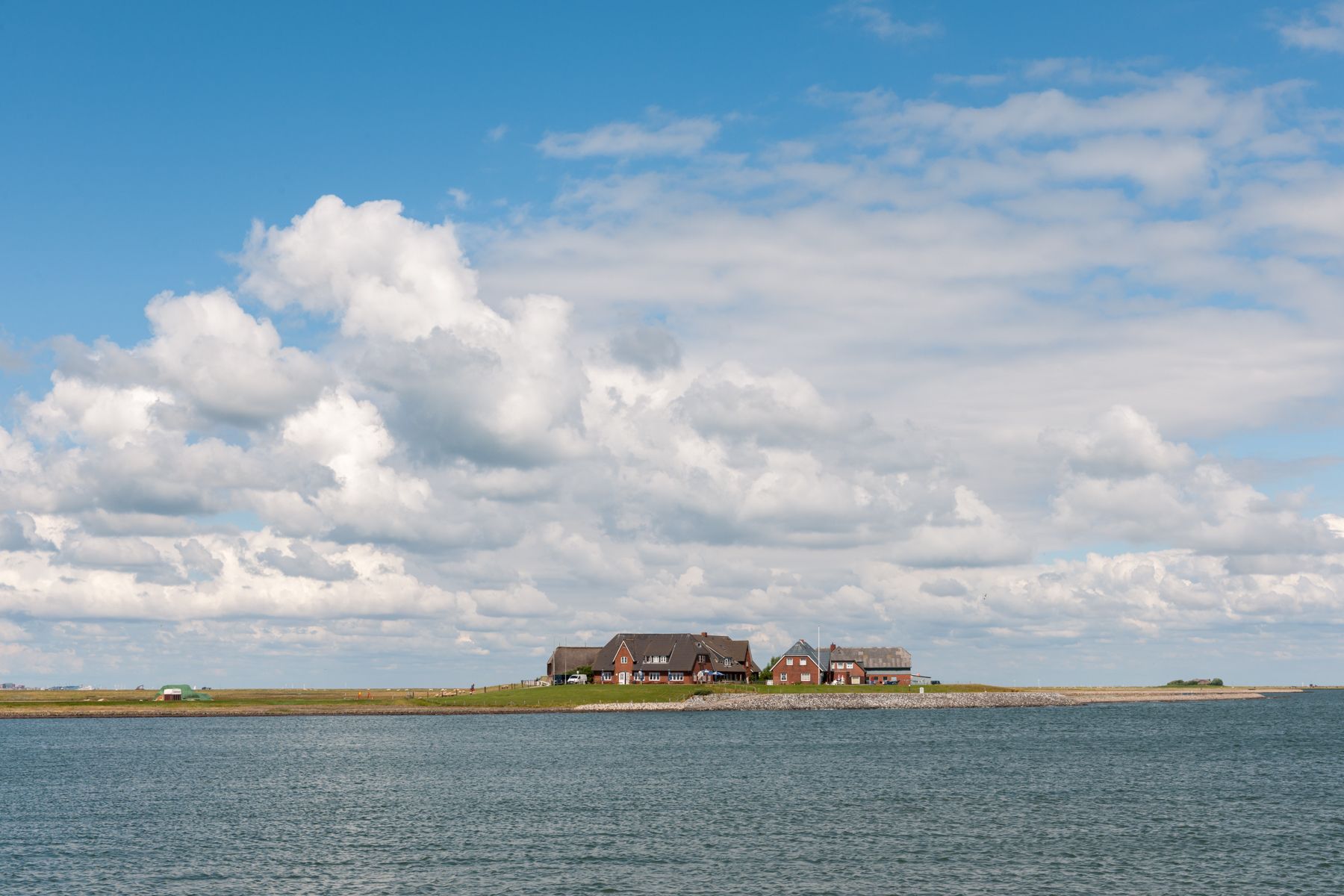 Blick auf eine Warft auf der Hallig Langeness vom Wasser auf