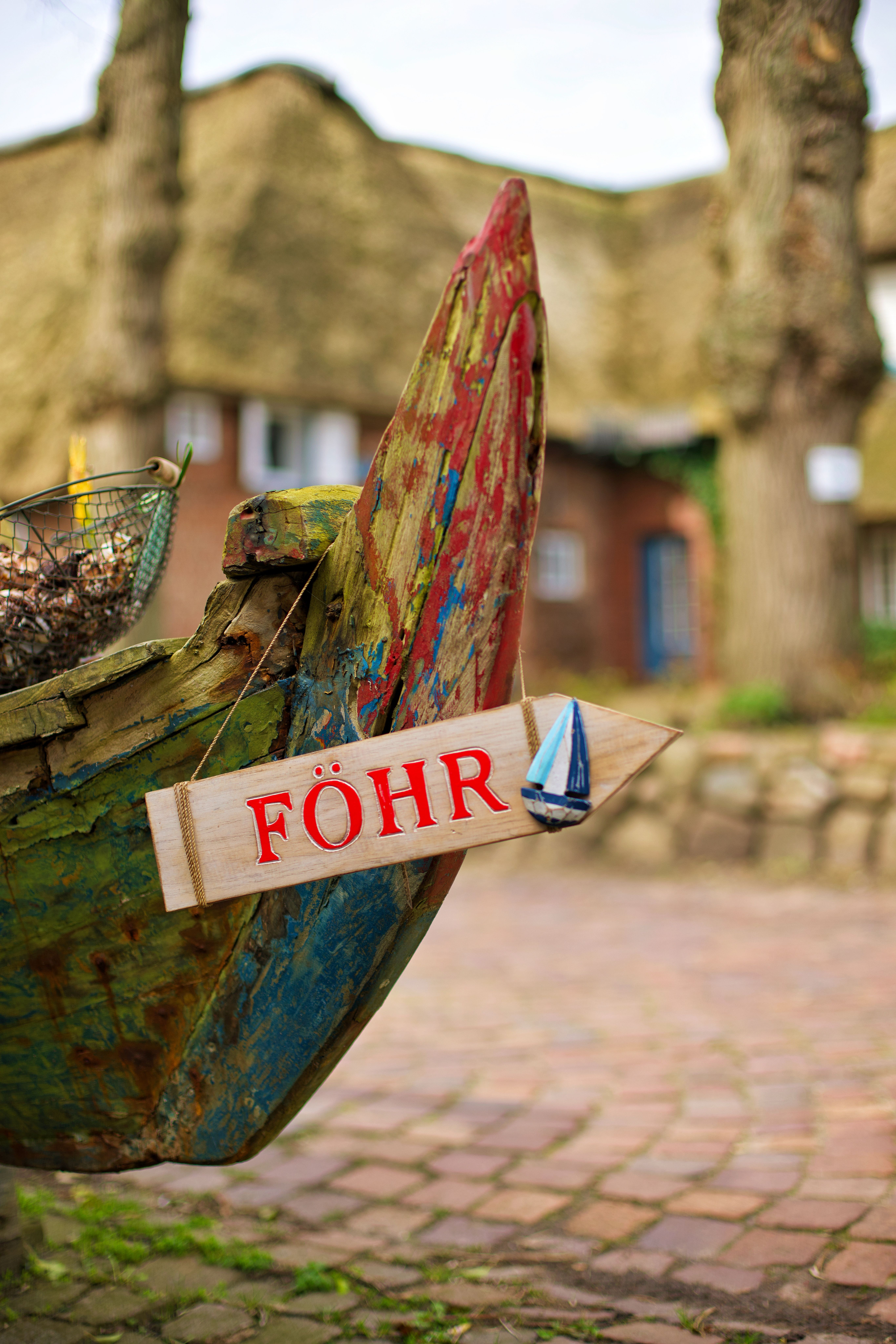 An dem Bug eines alten Ruderbootes, hängt ein buntes hölzernes Schild mit der Aufschrift Föhr. Foto: Gary Asmussen