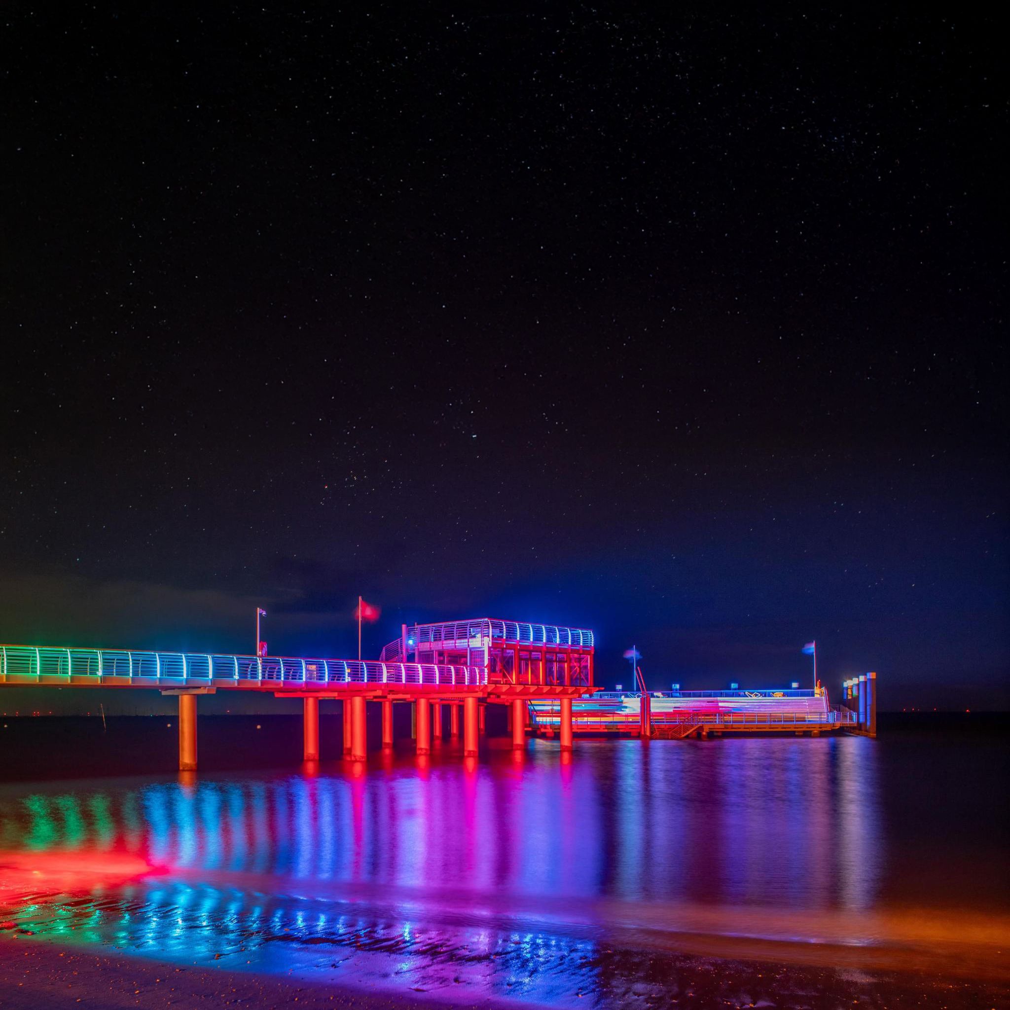 Die neue Mittelbrücke in Wyk illuminiert mit bunten Farben, die sich im Wasser spiegeln. Foto: kystlys