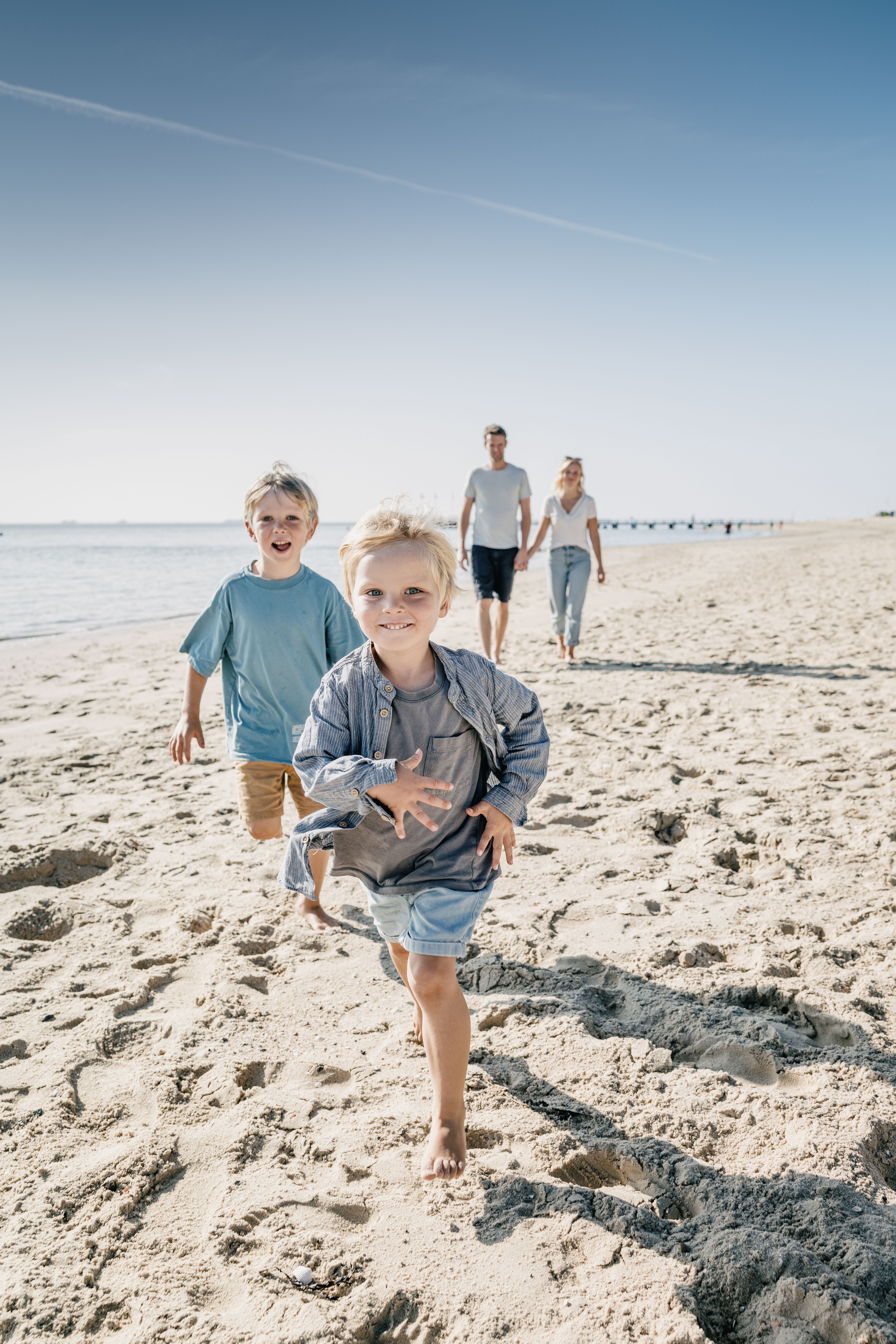 Eine Familie mit zwei Kindern läuft am Strand von Föhr