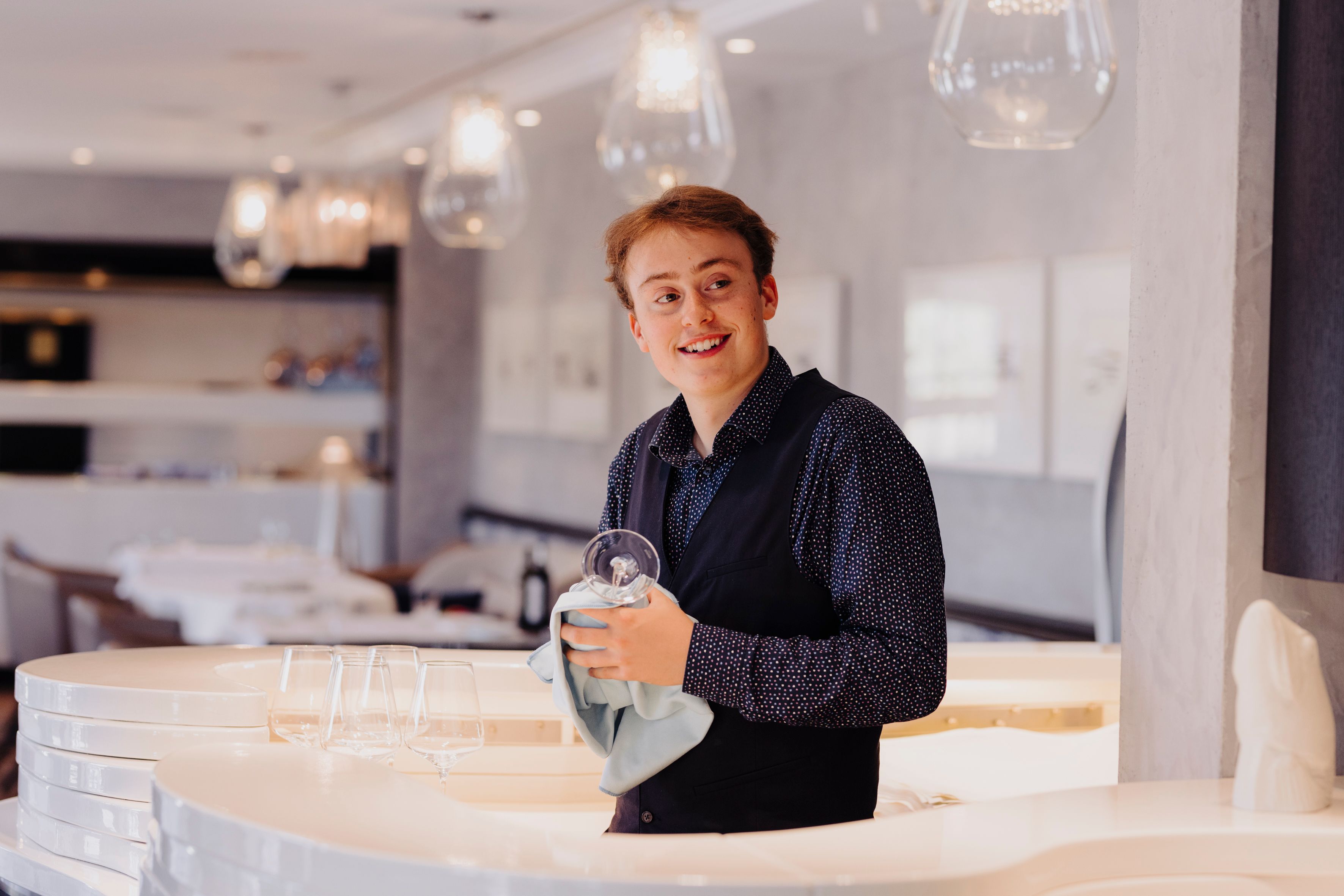 Ein Auszubildender putzt Weingläser im Sylter Söl'ring Hof