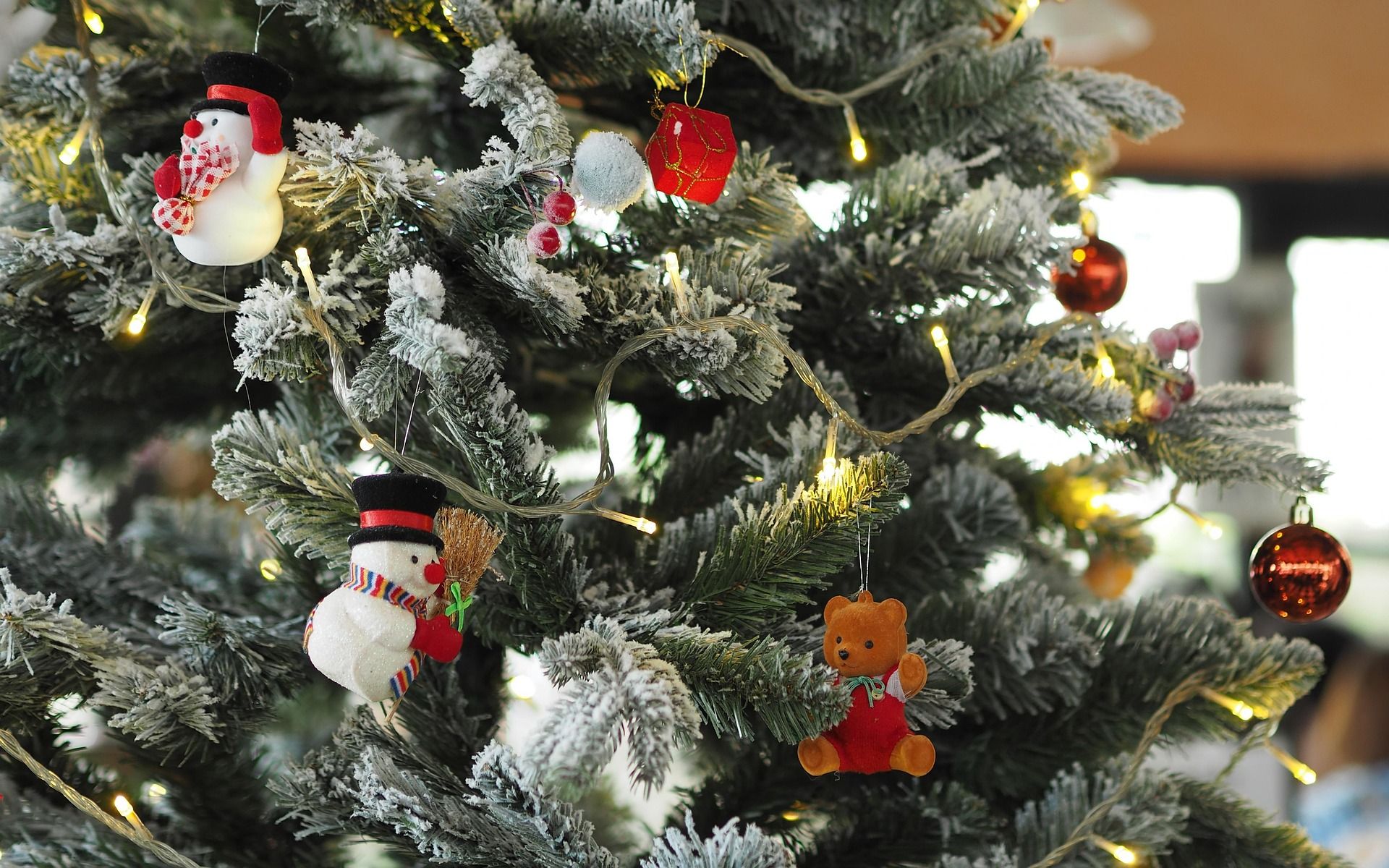 Im Weihnachtsbaum hängen Lichterketten sowie Schneemänner und ein kleiner Bär