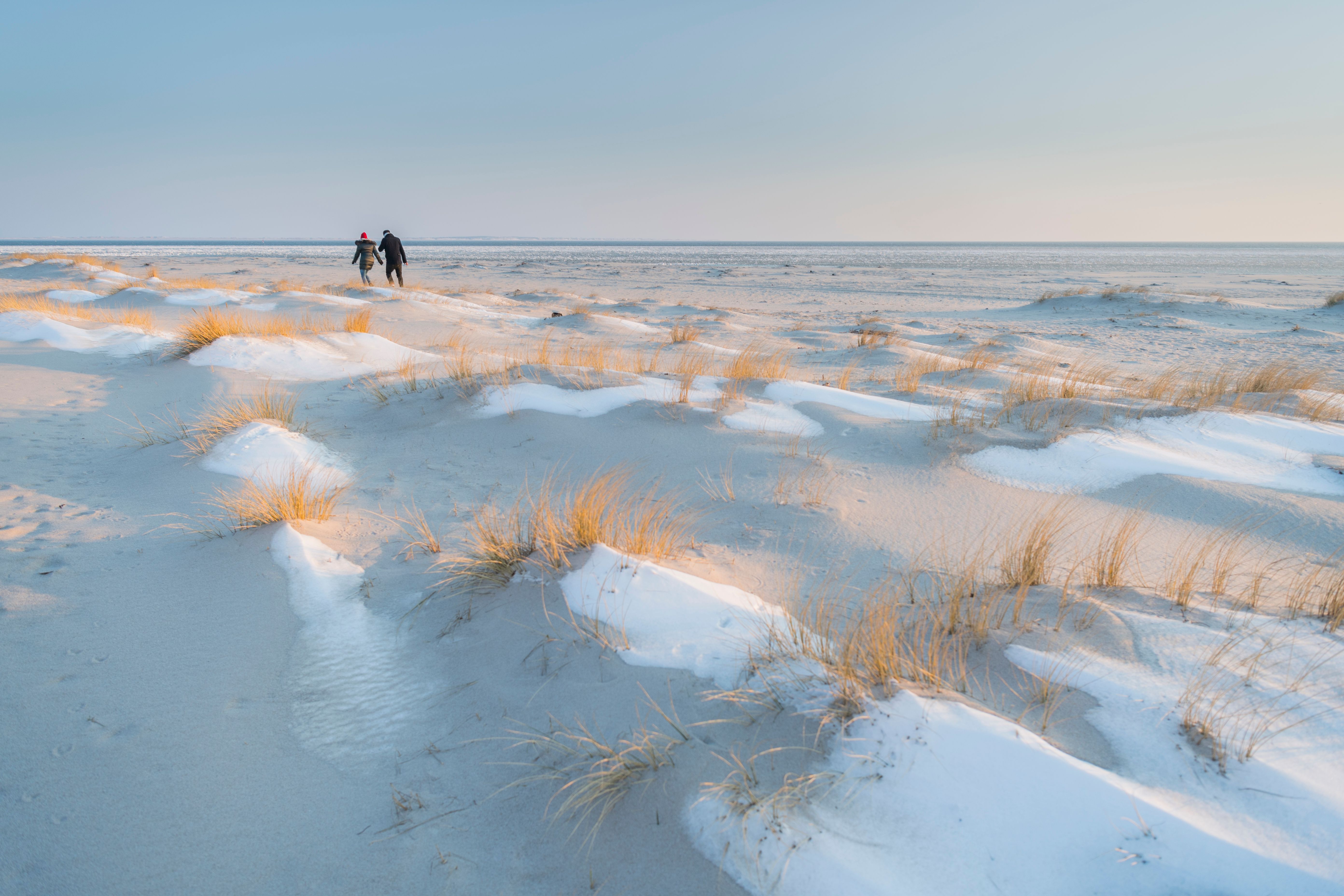 Ein Pärchen spaziert im Winter über die Dünen am Strand von Hörum auf Sylt