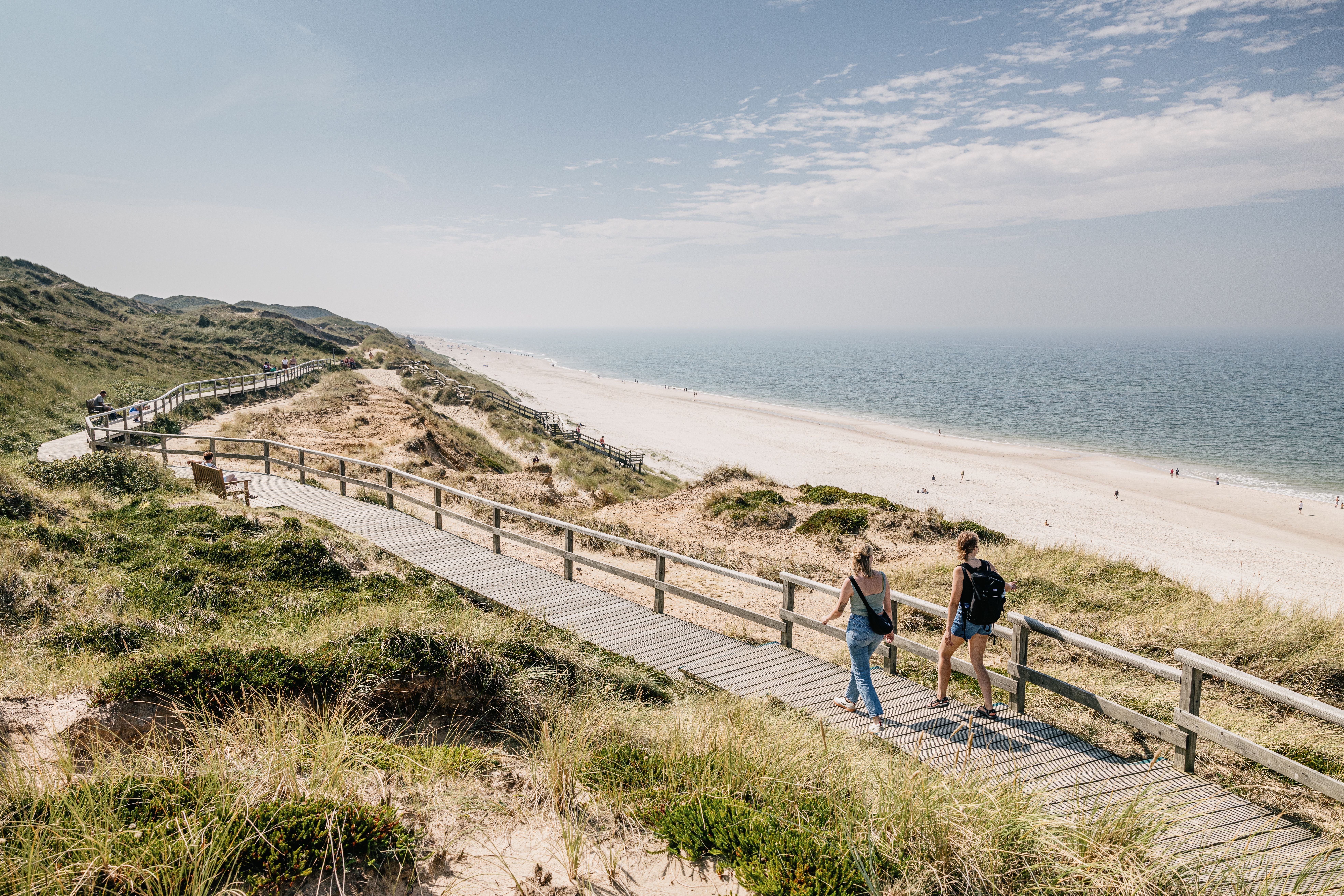 Ein Paar wandert durch die Dünenlandschaft von Sylt mit Blick aufs Meer