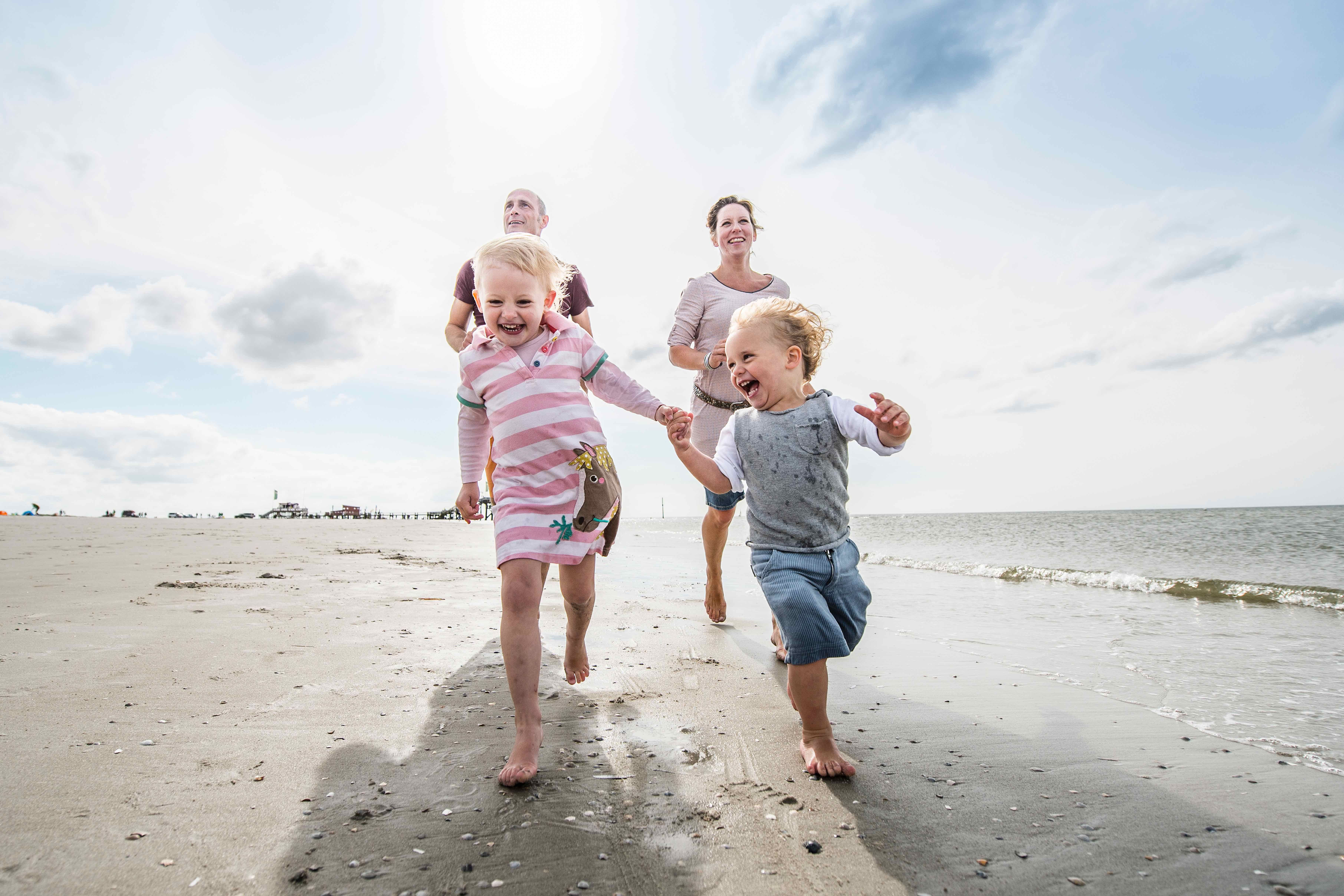 Familie läuft entlang der Wasserkante am Strand von SPO