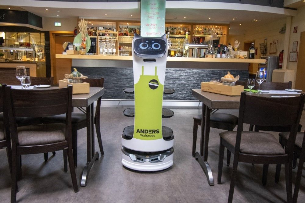 Ein Roboter, der als Kellner arbeitet, fährt zwischen den Tischen durch