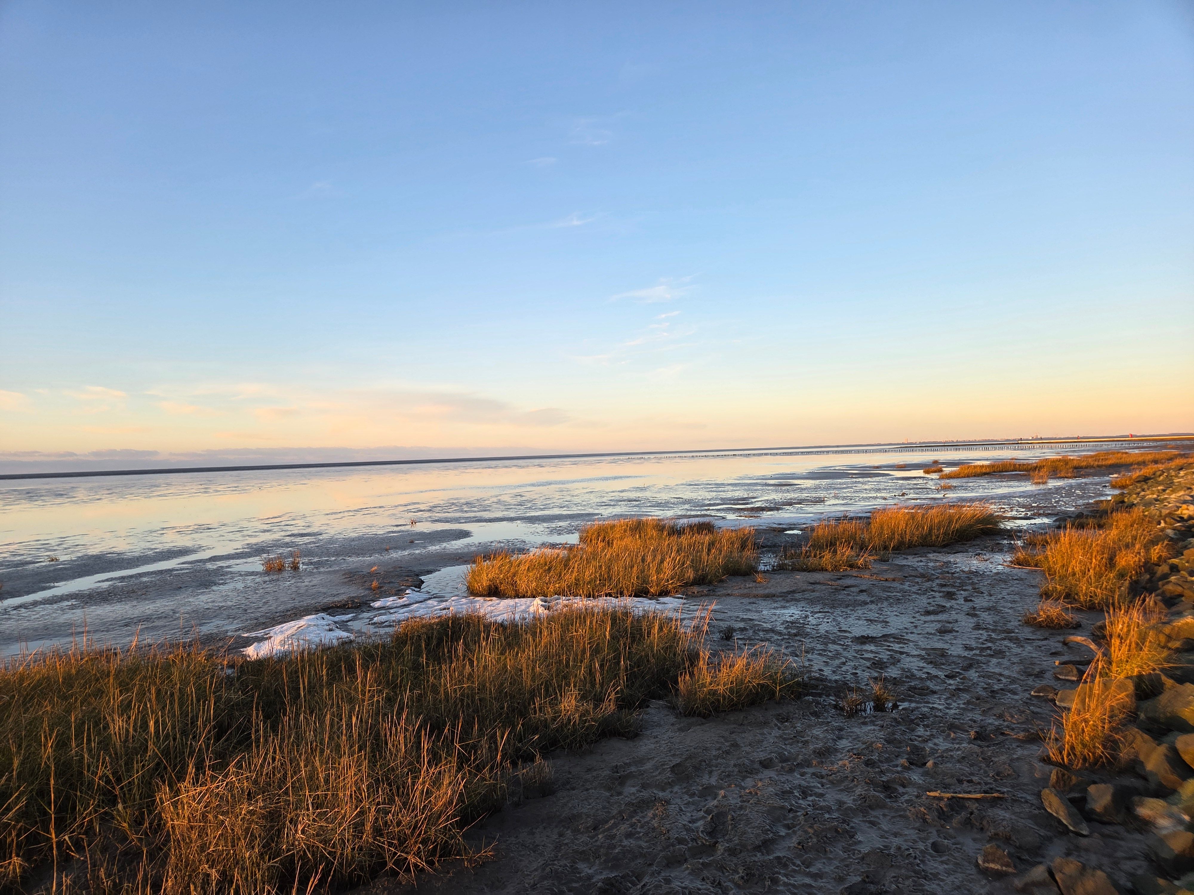 Blick über den winterlichen Deich in Friedrichskoog bei Abenddämmerung.