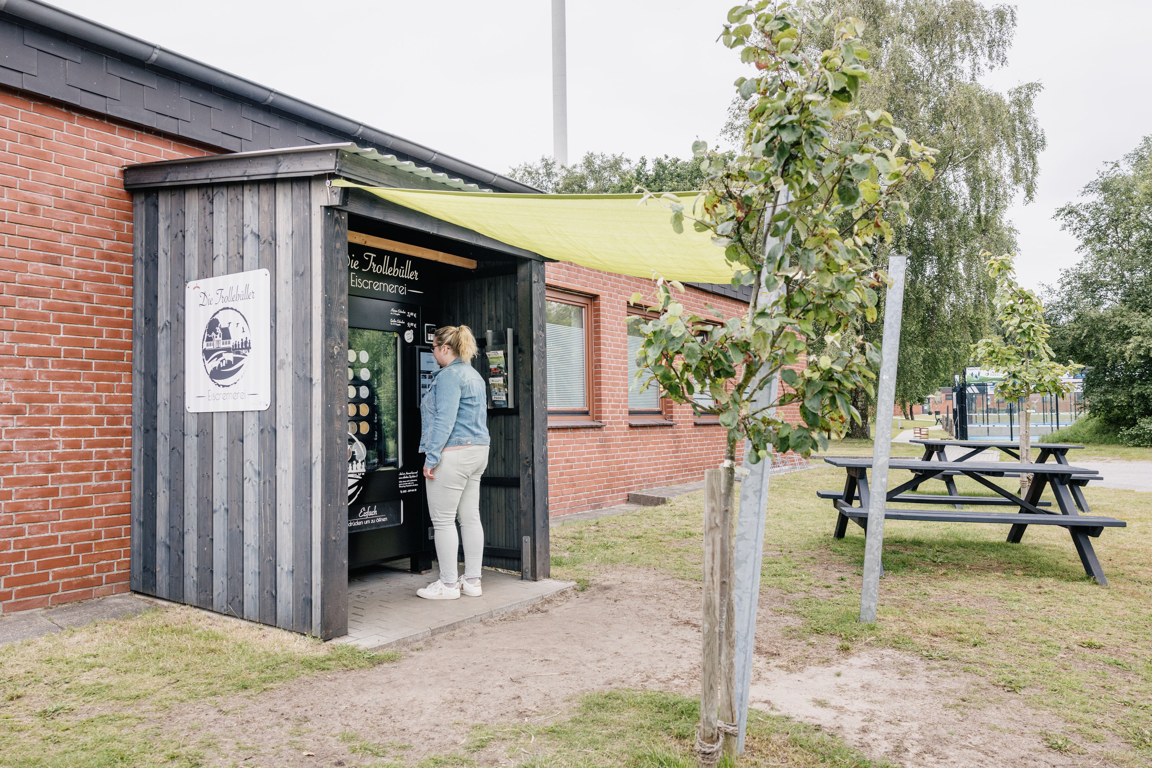 Eine Frau steht vor dem Selbstbedienungsautomaten der Trollebüller Eiscremerei auf dem GreenTEC Campus.