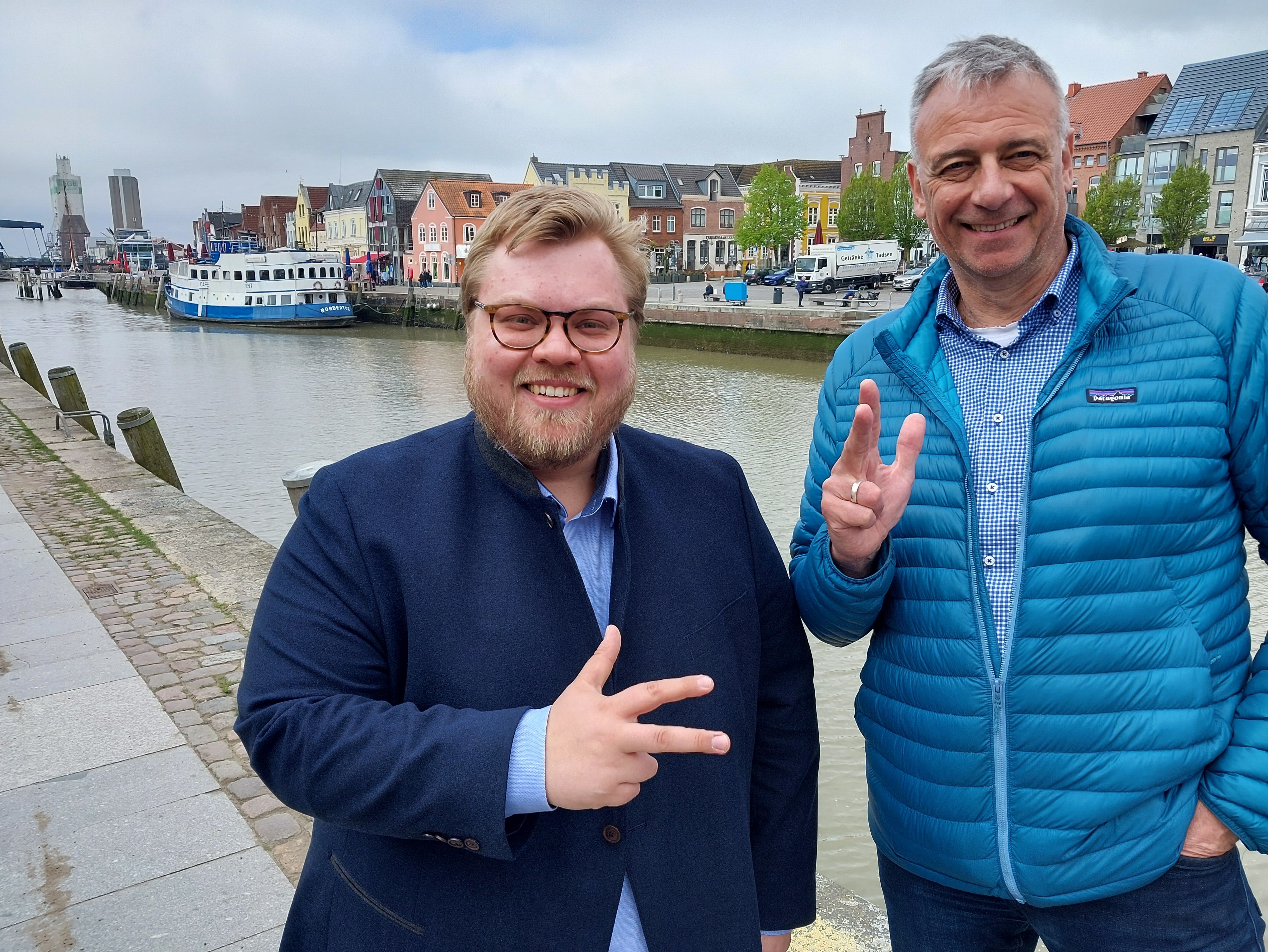Portrait Leif Bodin und Frank Ketter. Sie halten drei Finger in die Luft, um ihre Teilnahme an der Müllsammelaktion "Nimm Drei - sei dabei" zu symbolisieren.