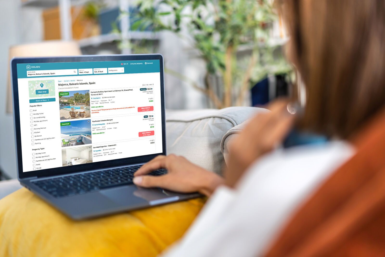 Eine Frau hat auf ihrem Laptop die Buchungsstrecke von Holidu geöffnet