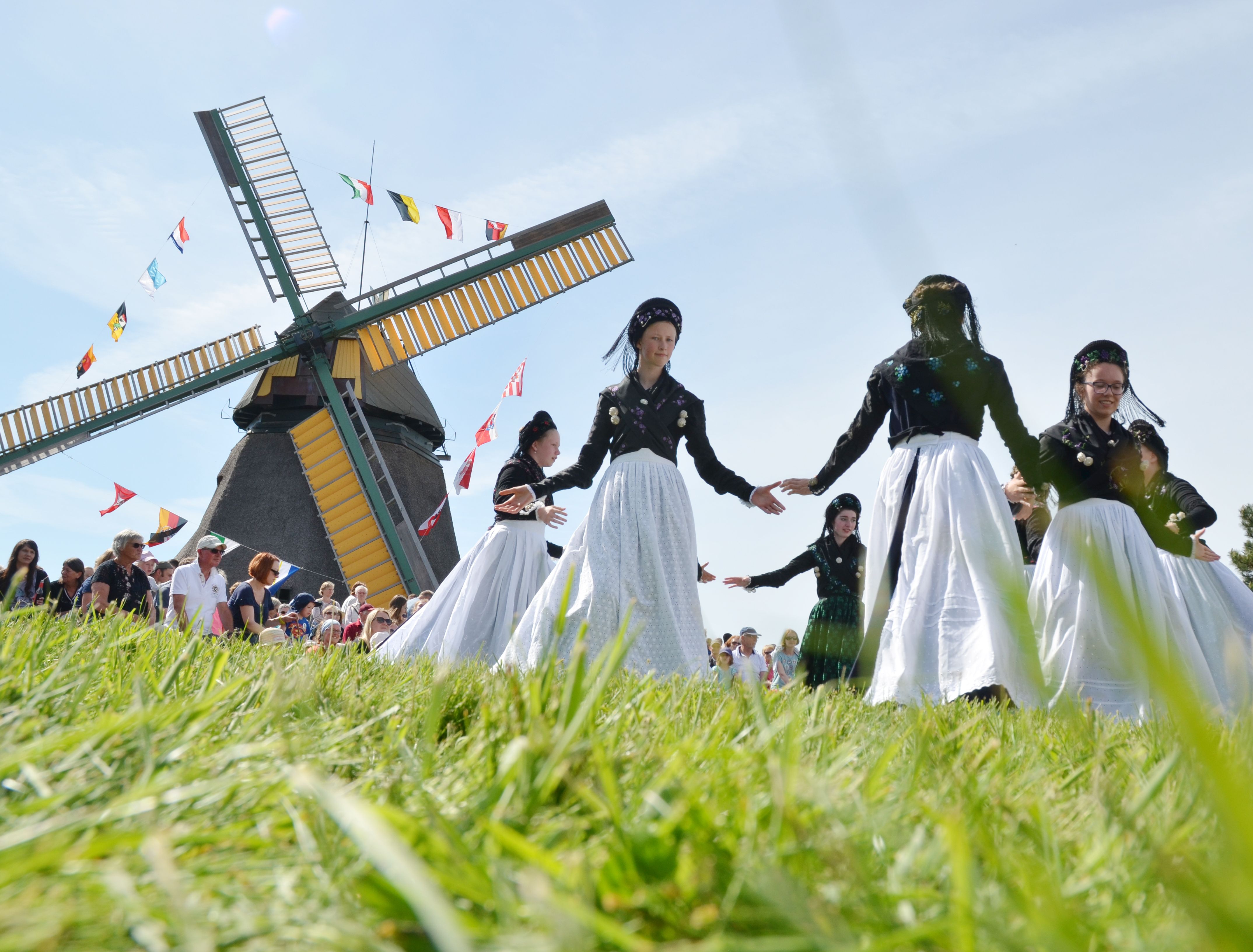 Traditionell gekleidete Frauen tanzen vor einer Windmühle