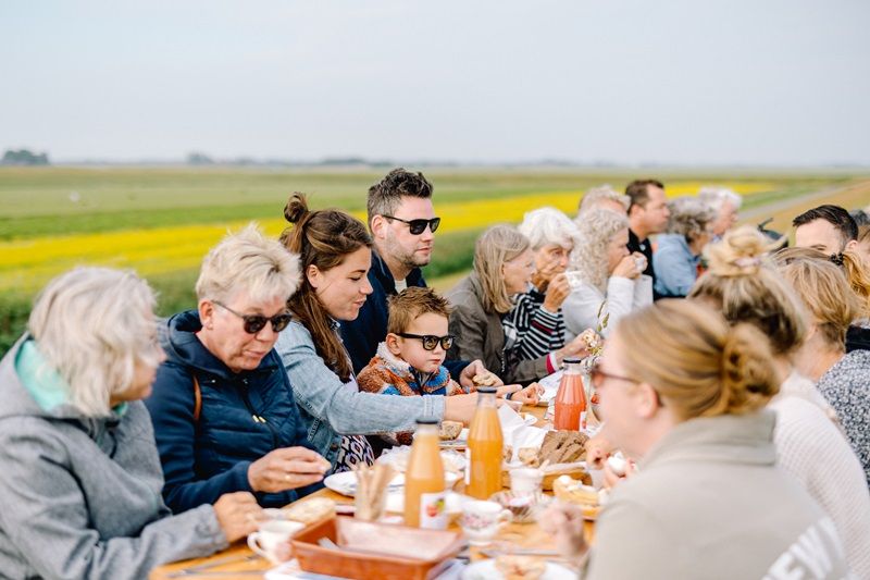 Menschen sitzen an einem Tisch und frühstücken gemeinsam auf dem Deich